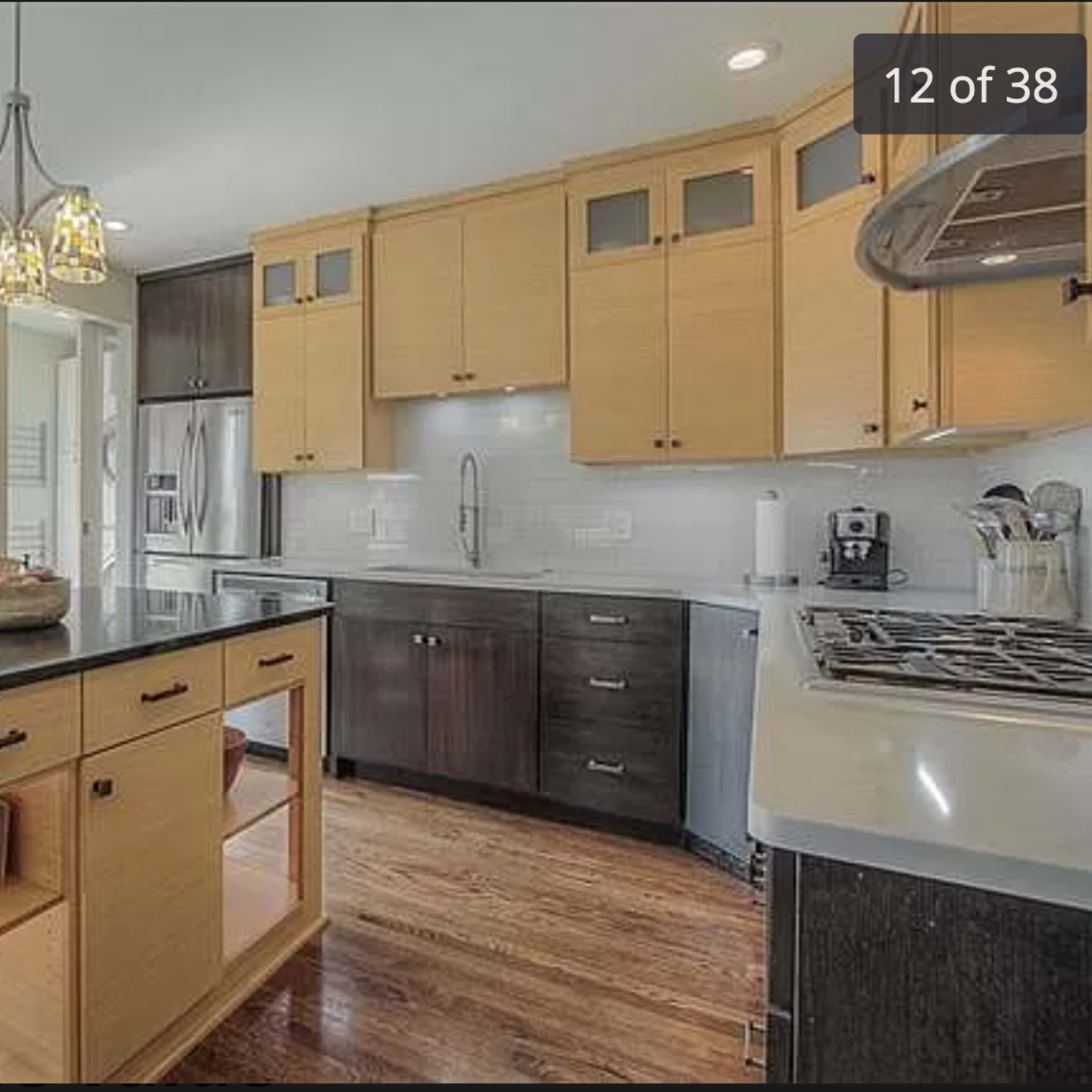 A modern kitchen featuring an island with storage, light wood cabinets, and stainless steel appliances.