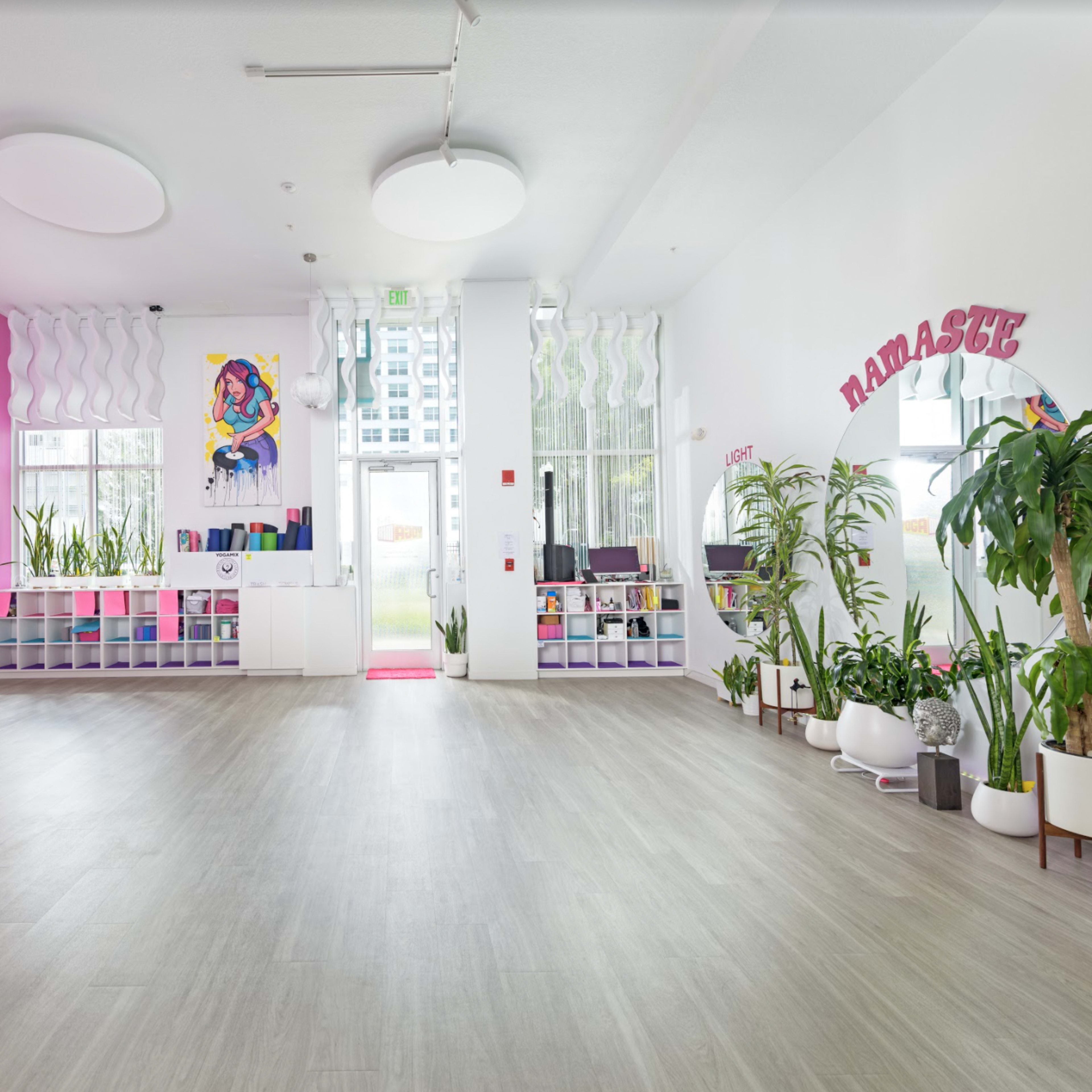 A spacious, bright room with pink walls, various plants, and an entryway featuring the word "Namaste."