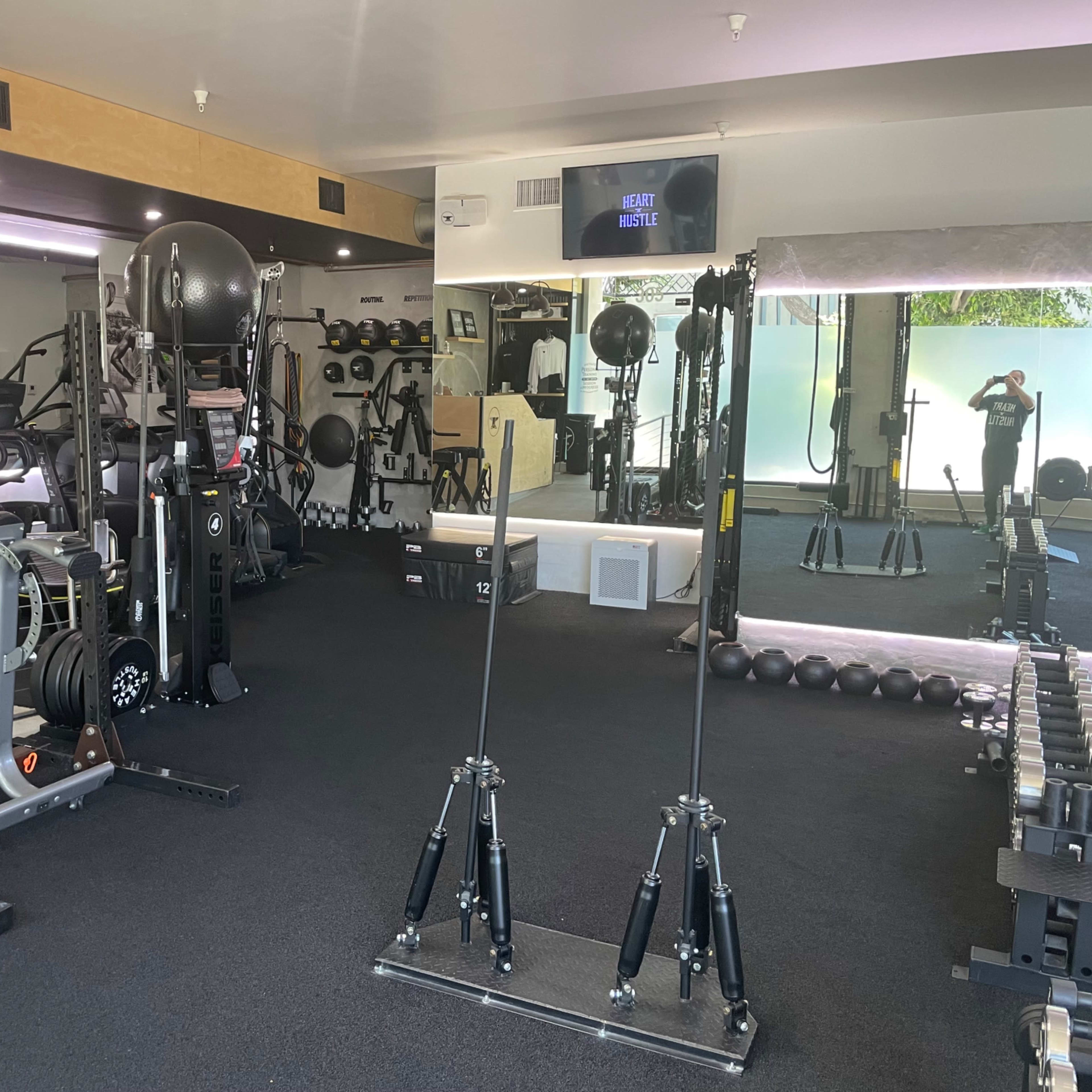 A well-equipped gym interior featuring various exercise machines, weights, and workout stations.