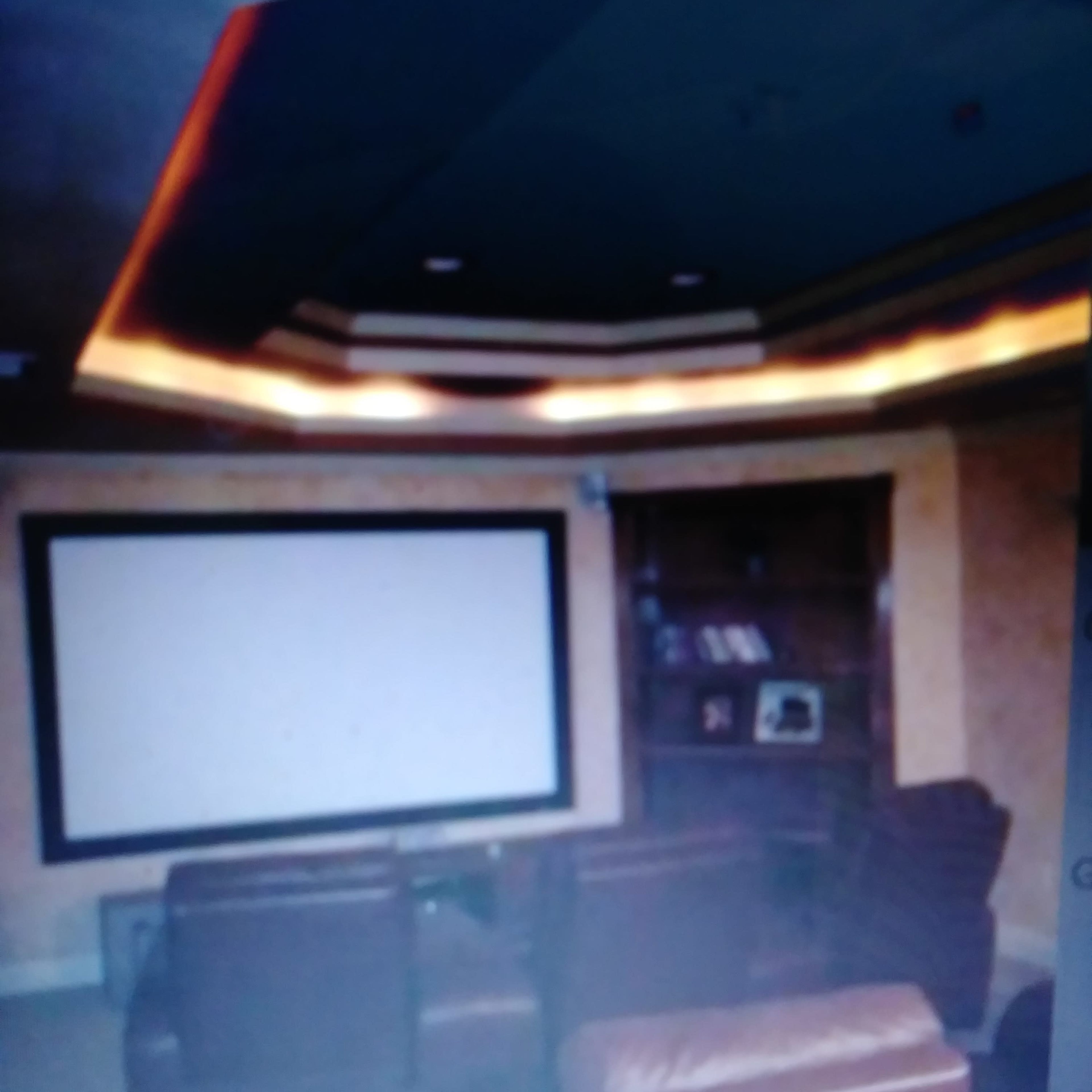 A home theater with leather chairs facing a large blank screen and a bookshelf in the corner.
