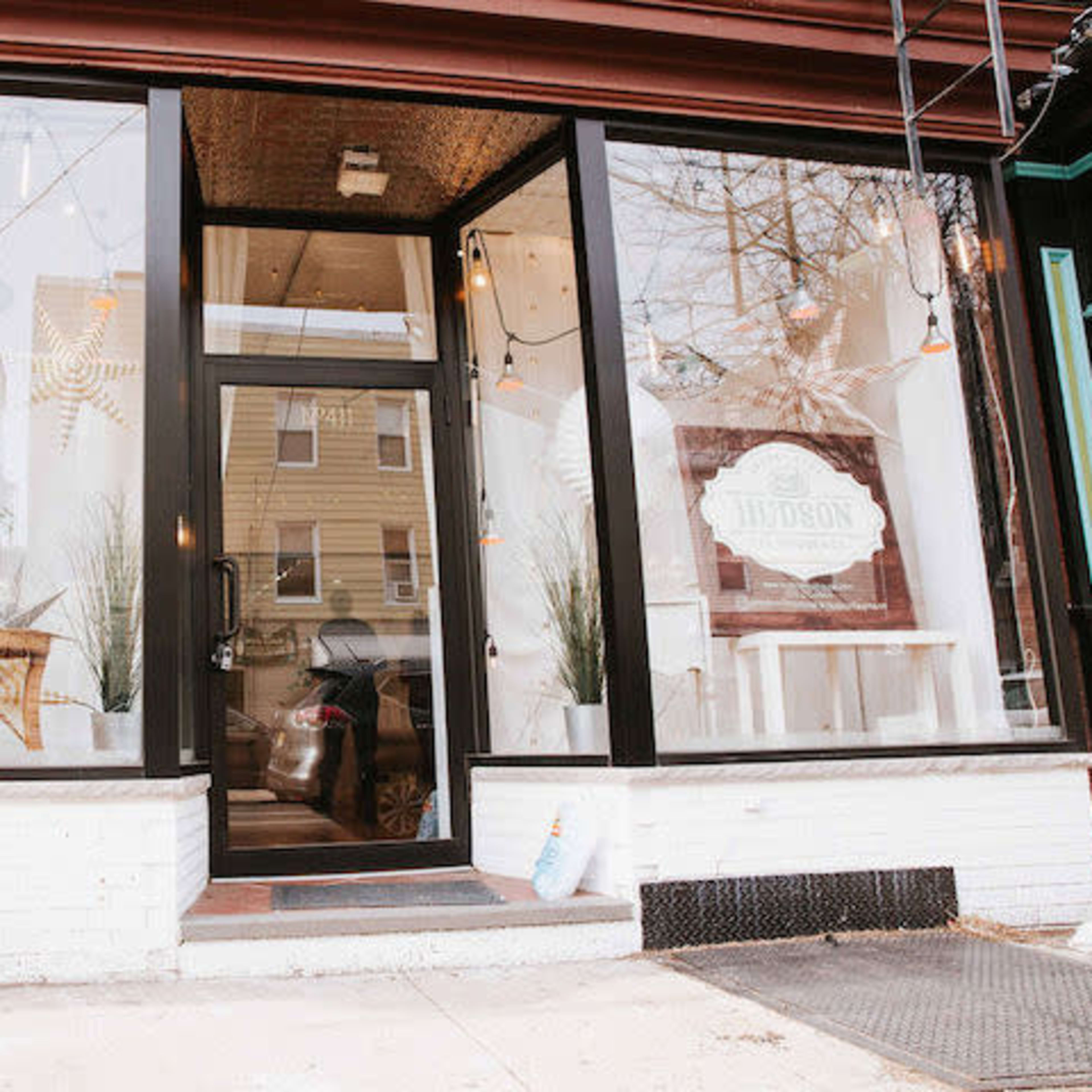 A storefront with large glass windows, featuring minimalist interior decor and a sign that reads "Hiverson."