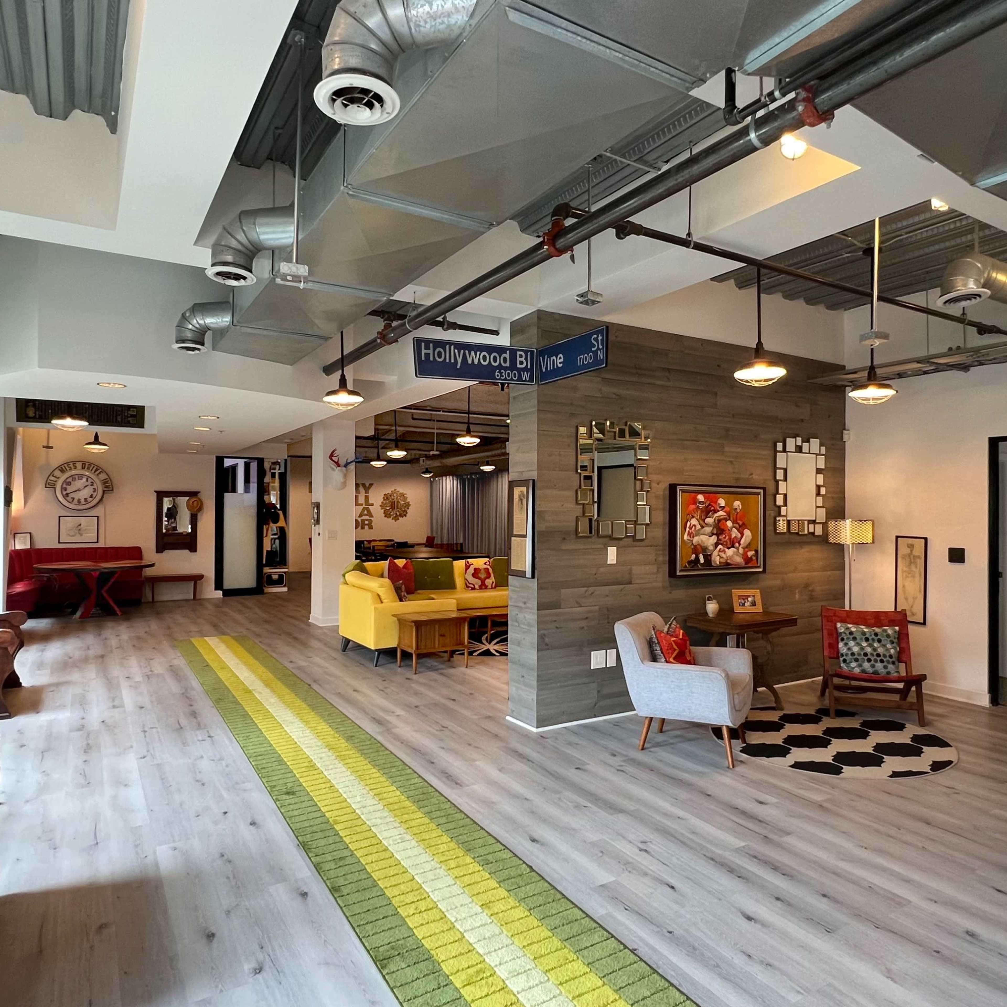 A modern open-concept living space with a mix of seating areas, decorative walls, and a vibrant green runner along the floor.