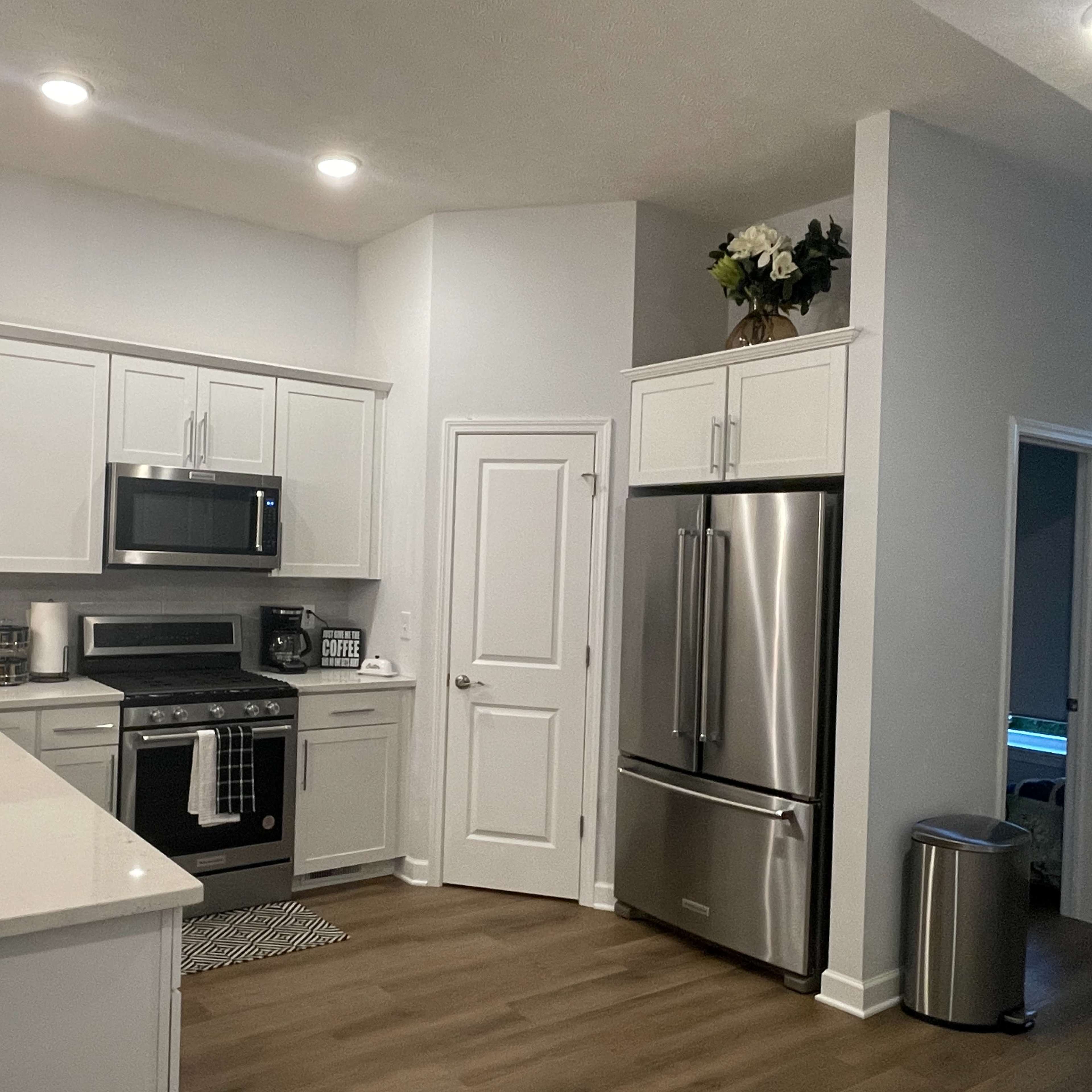A modern kitchen with white cabinets, stainless steel appliances, and a spacious layout featuring an island with a sink.