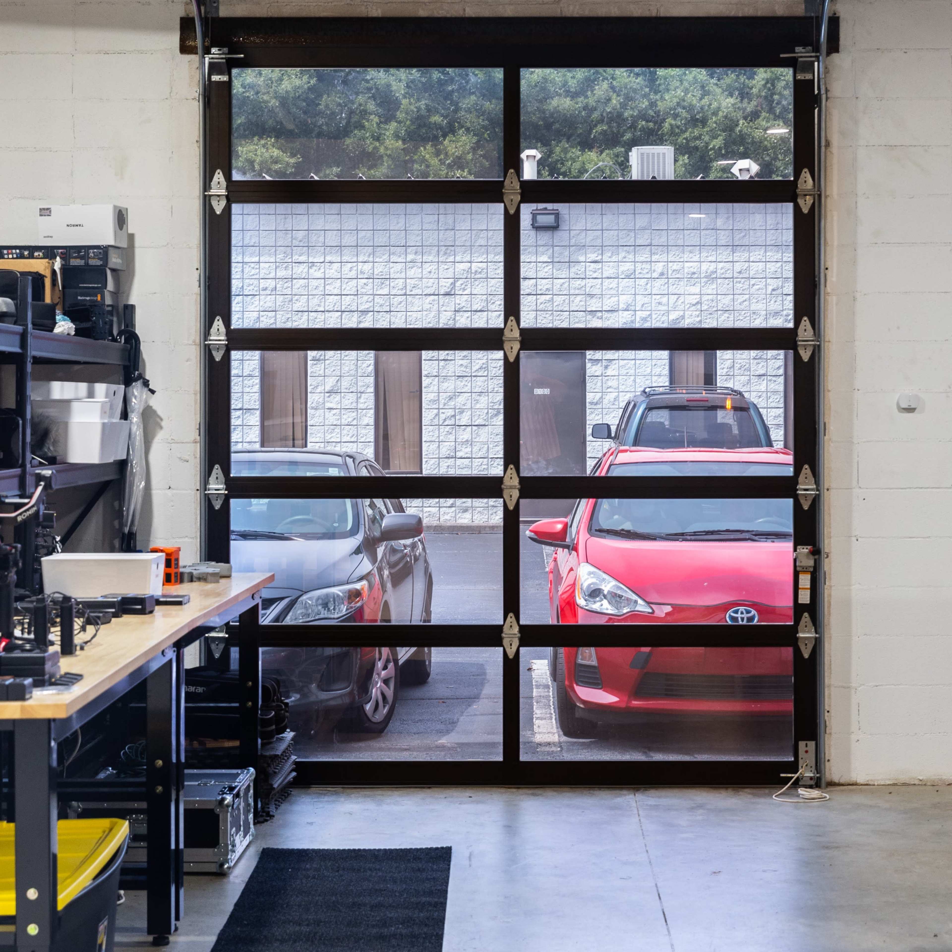 A garage with a view of two parked cars through a large windowed garage door.
