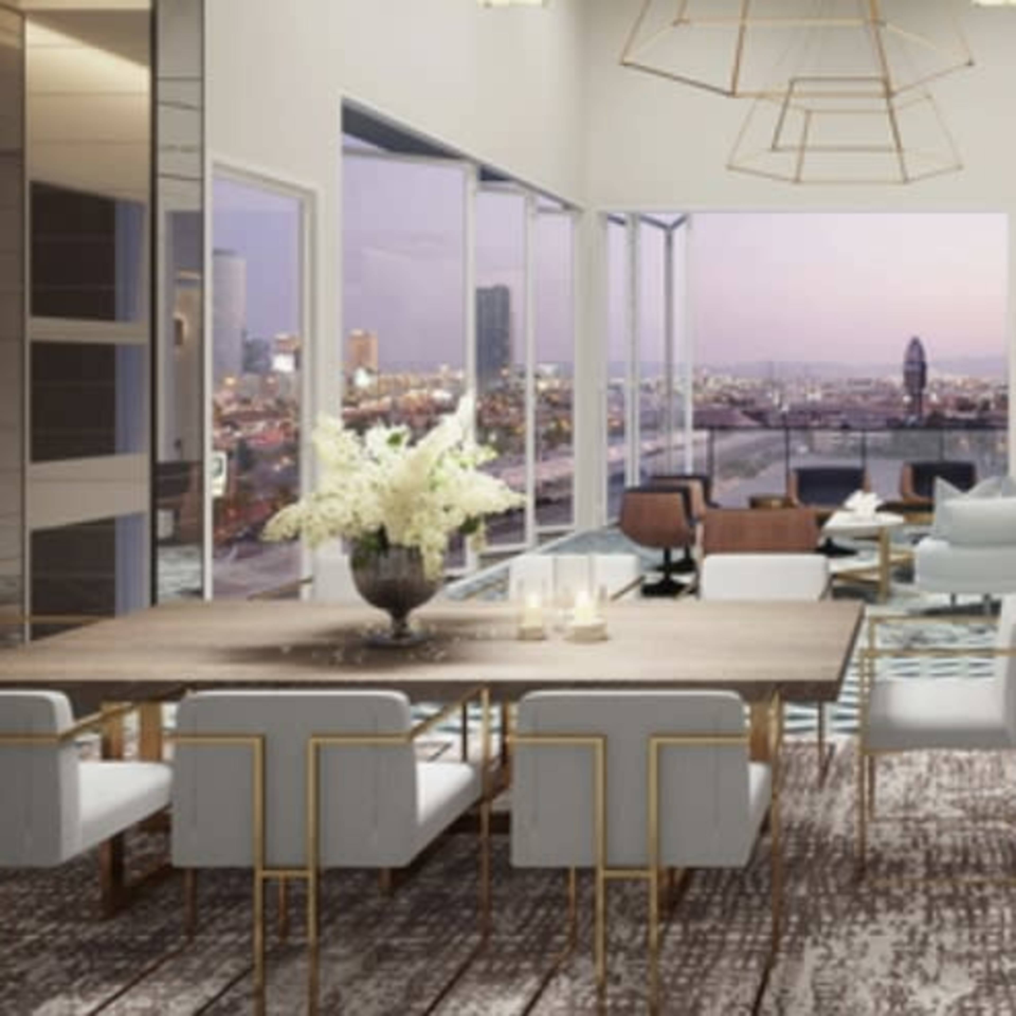 A modern, open-concept lounge area with a large dining table, stylish seating, and floor-to-ceiling windows offering a view of a city skyline.