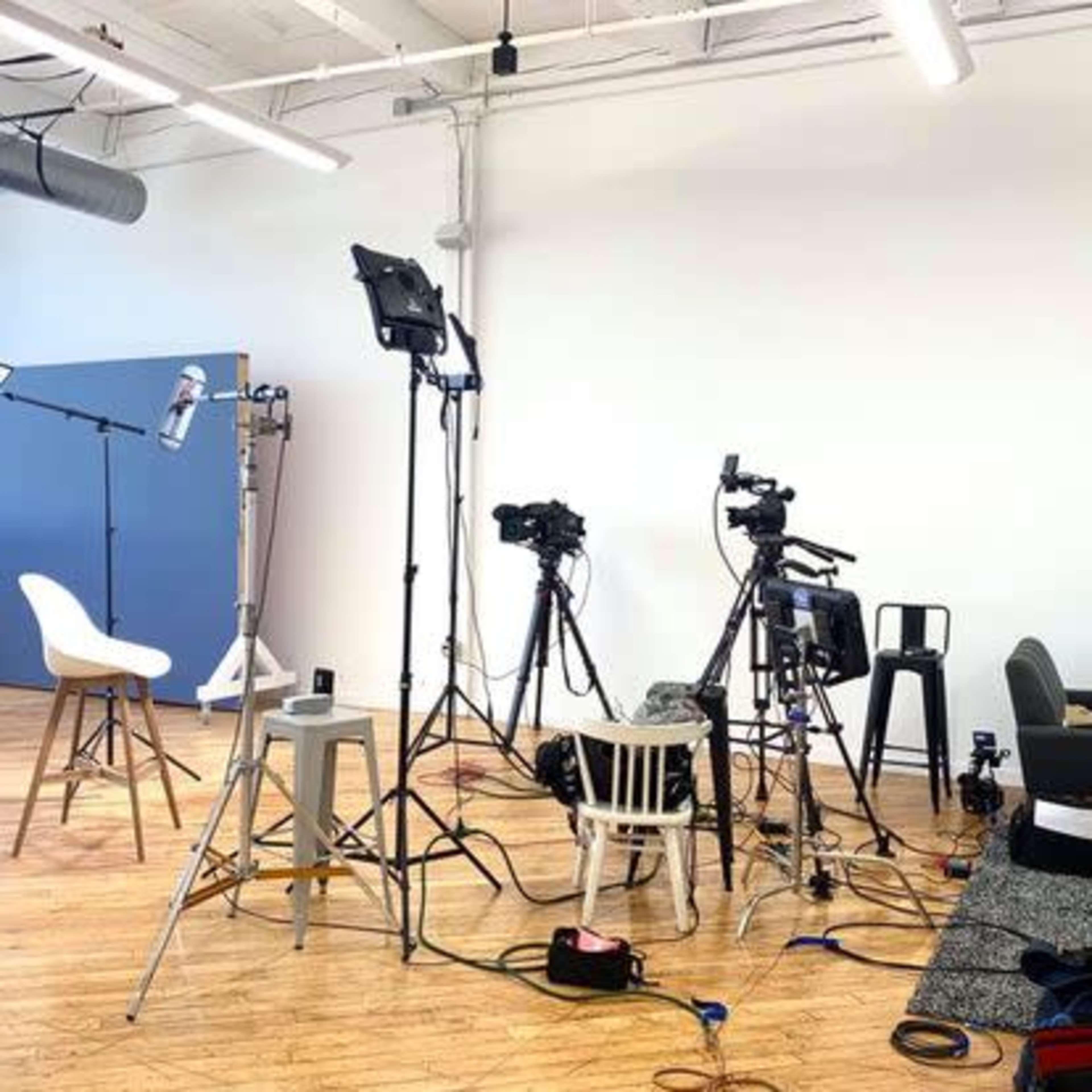 A video recording setup with multiple cameras and lighting equipment arranged in a studio space.