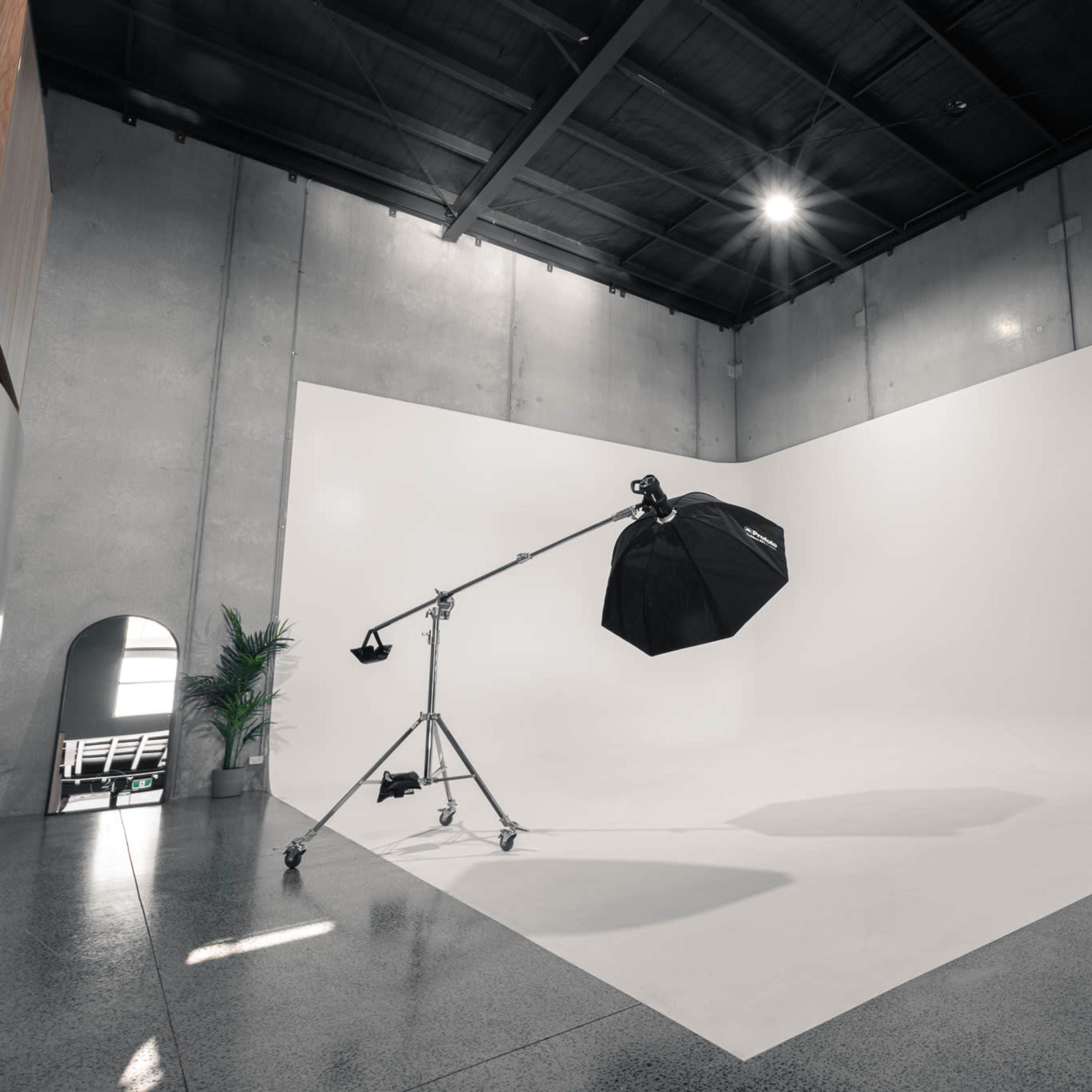 A spacious photography studio with a large white backdrop, lighting equipment, and a vanity mirror setup.