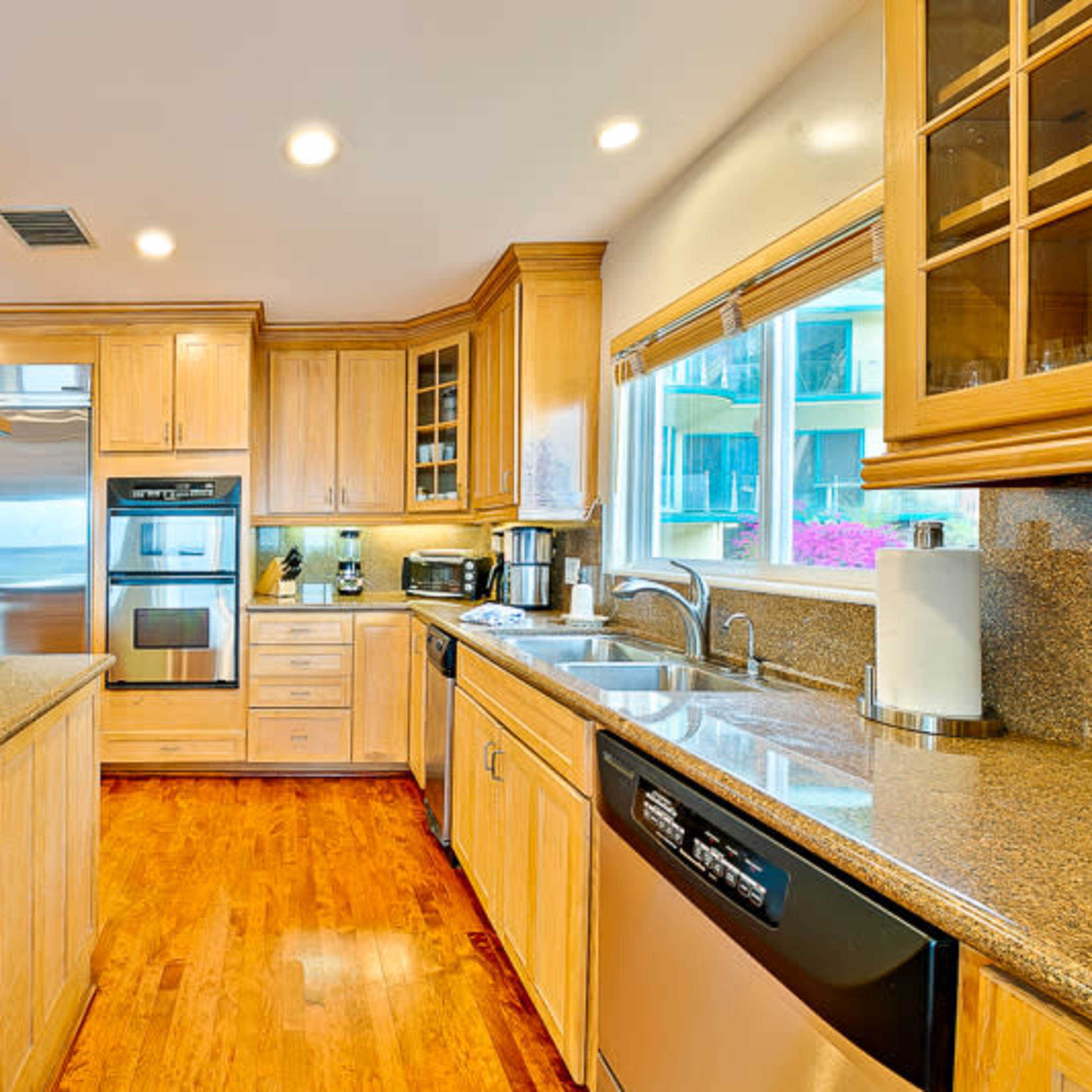 A modern kitchen with wooden cabinetry, stainless steel appliances, and a countertop that extends into a breakfast bar.