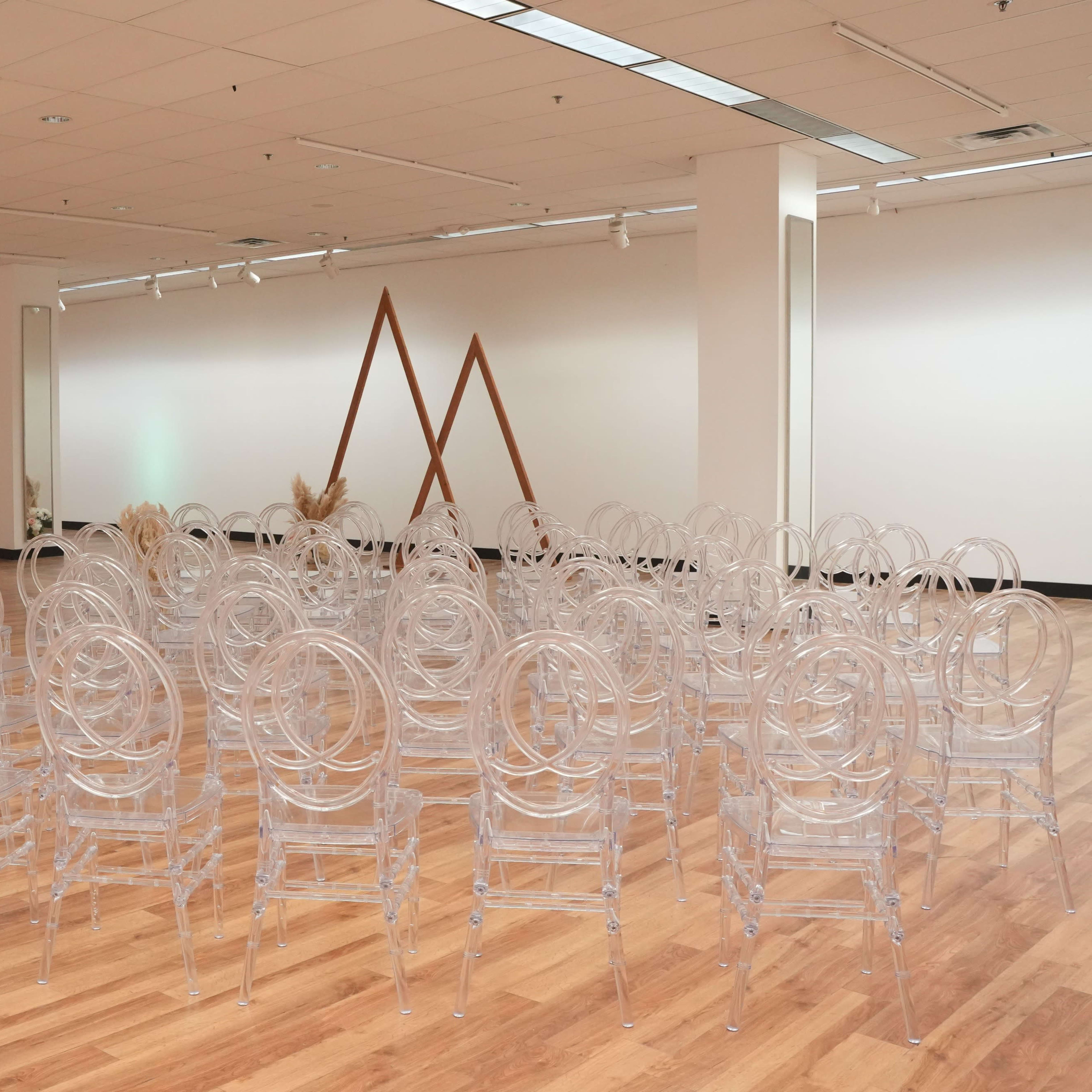 A spacious room set up with multiple rows of transparent chairs arranged for an event.