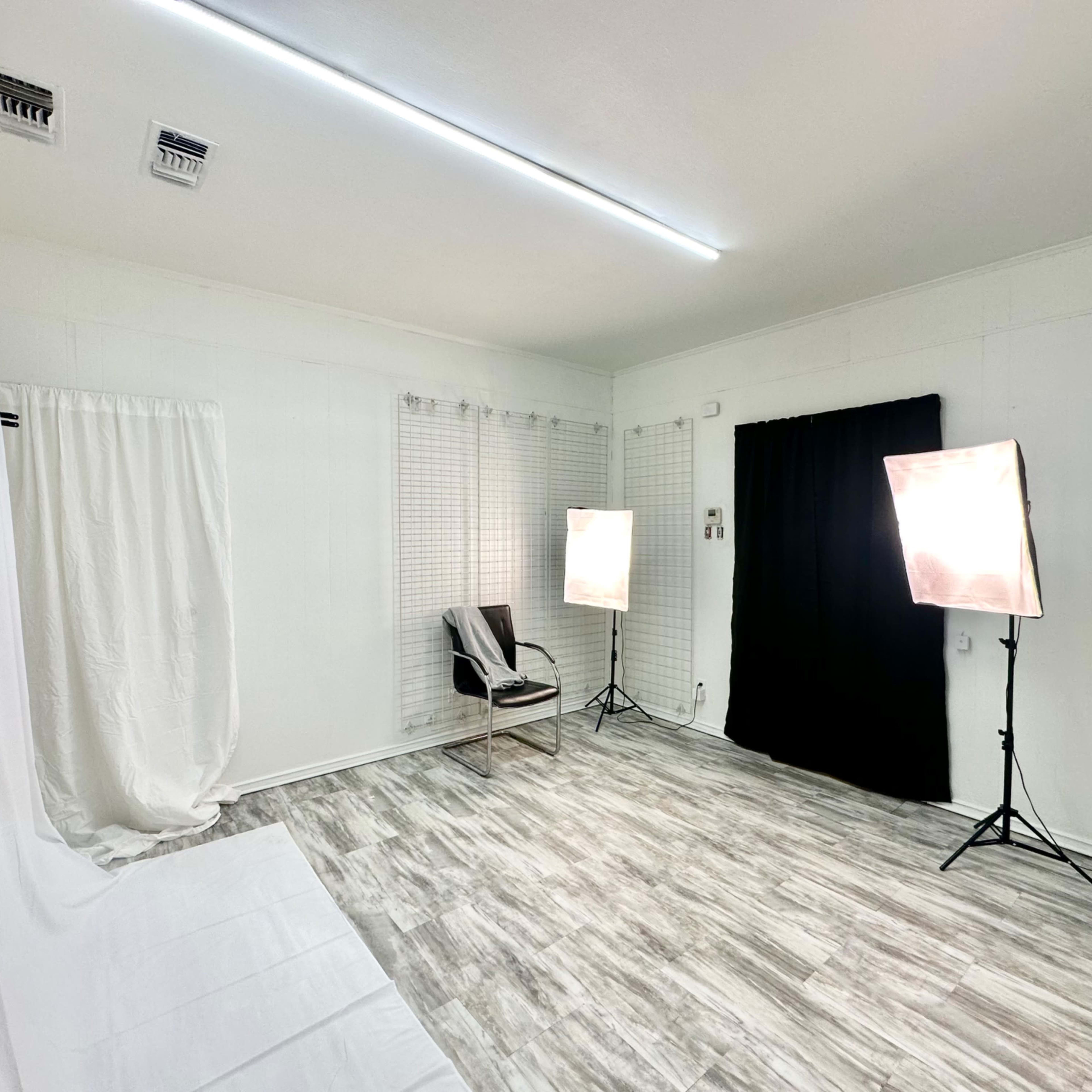 A bright studio space with a white backdrop, a black curtain, and two softbox lights positioned on either side.