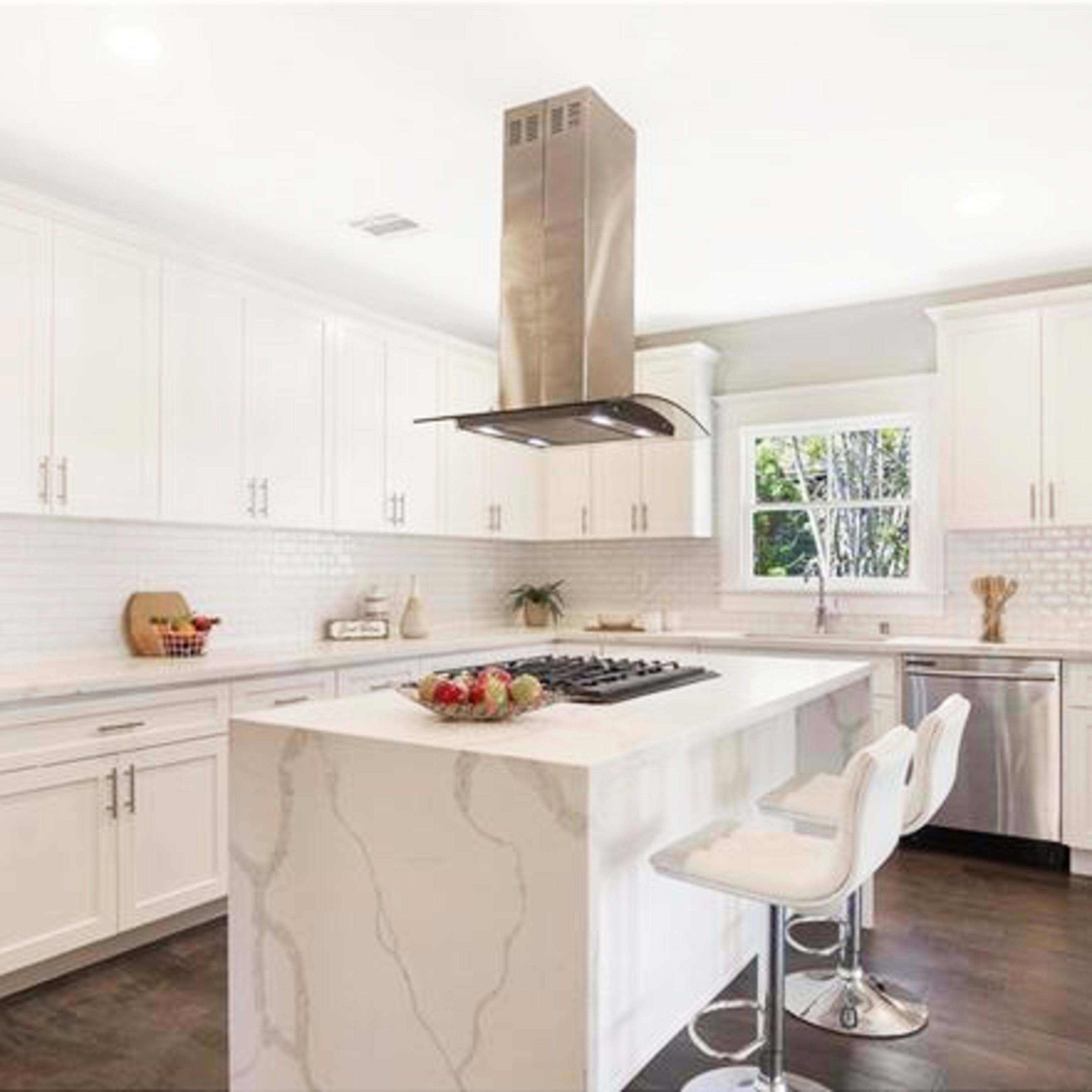 A modern kitchen with white cabinetry, a large island topped with marble, and stainless steel appliances.