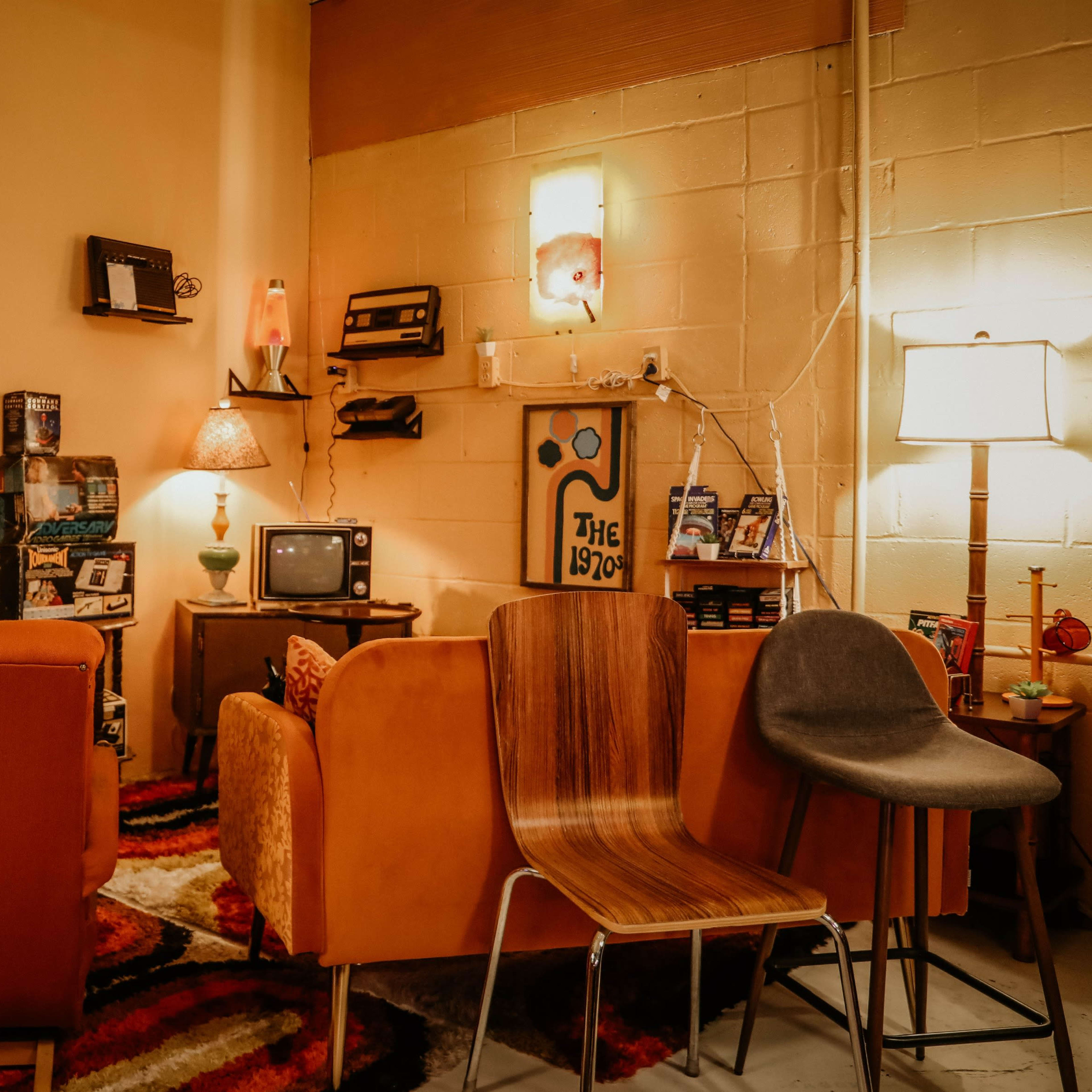A retro-themed living room with a collection of video games on a shelf, vintage furniture, and a small television set.