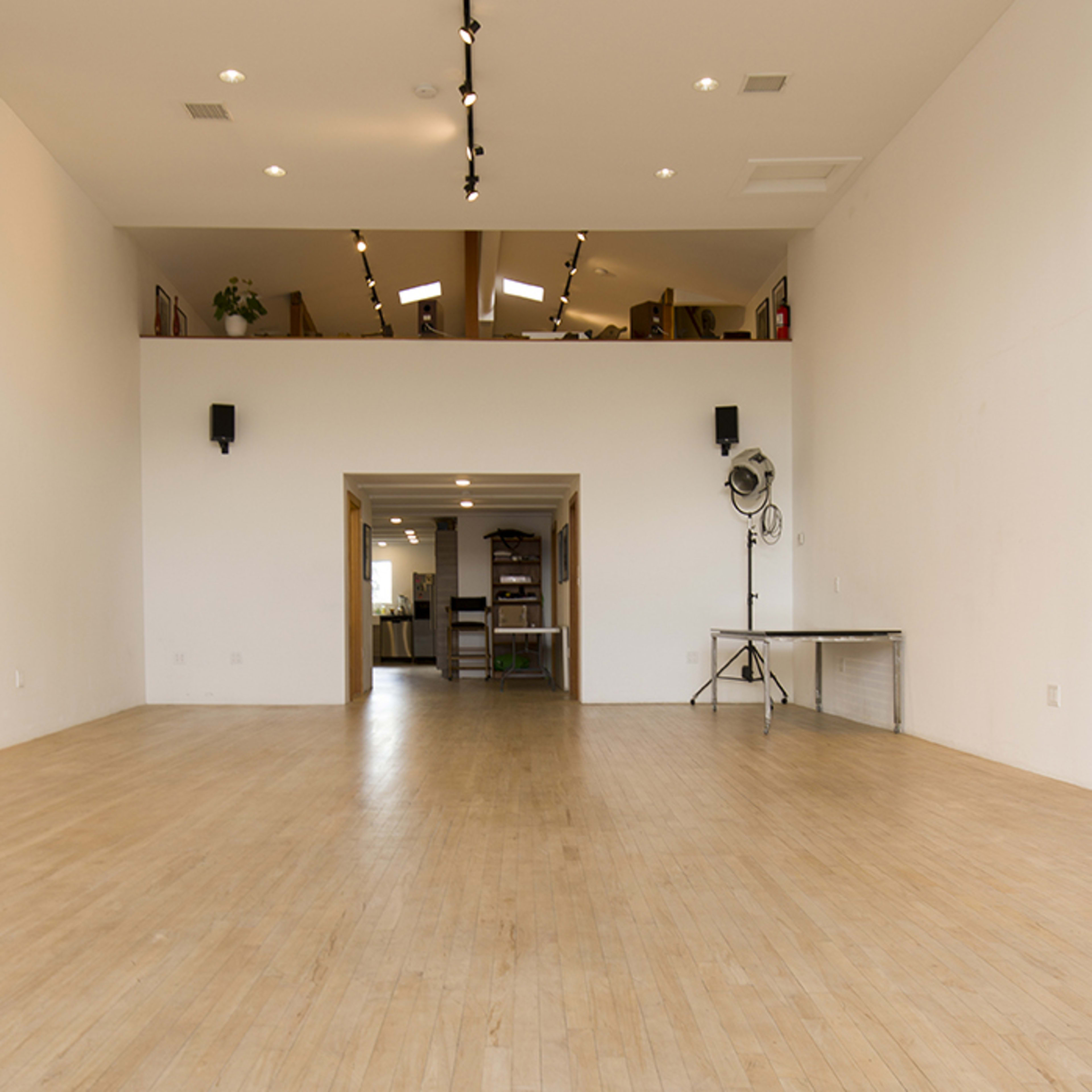 A spacious, empty room with wooden flooring and white walls, featuring a large opening leading to another area.