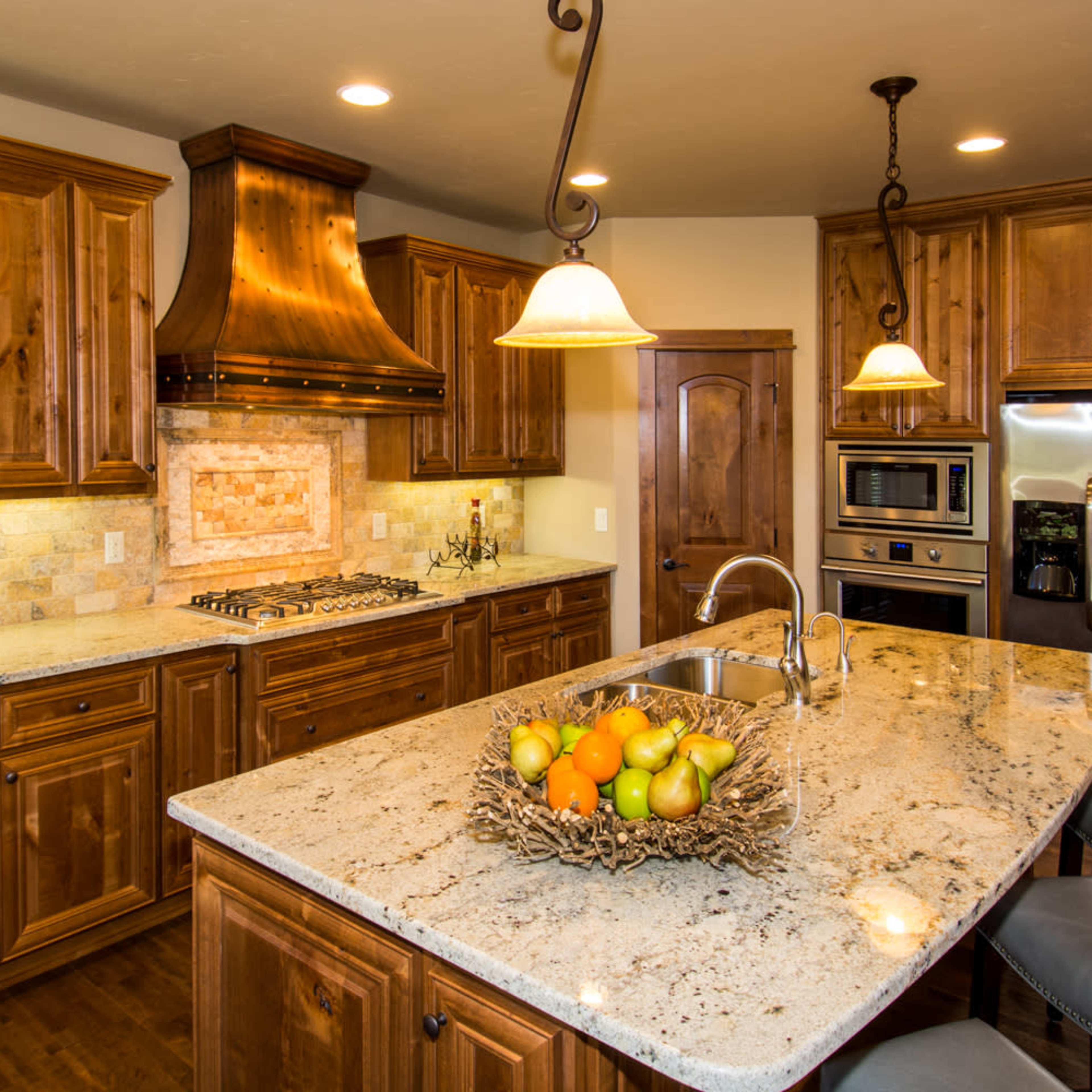 The kitchen features wooden cabinetry, a granite countertop island with a fruit bowl, and stainless steel appliances.