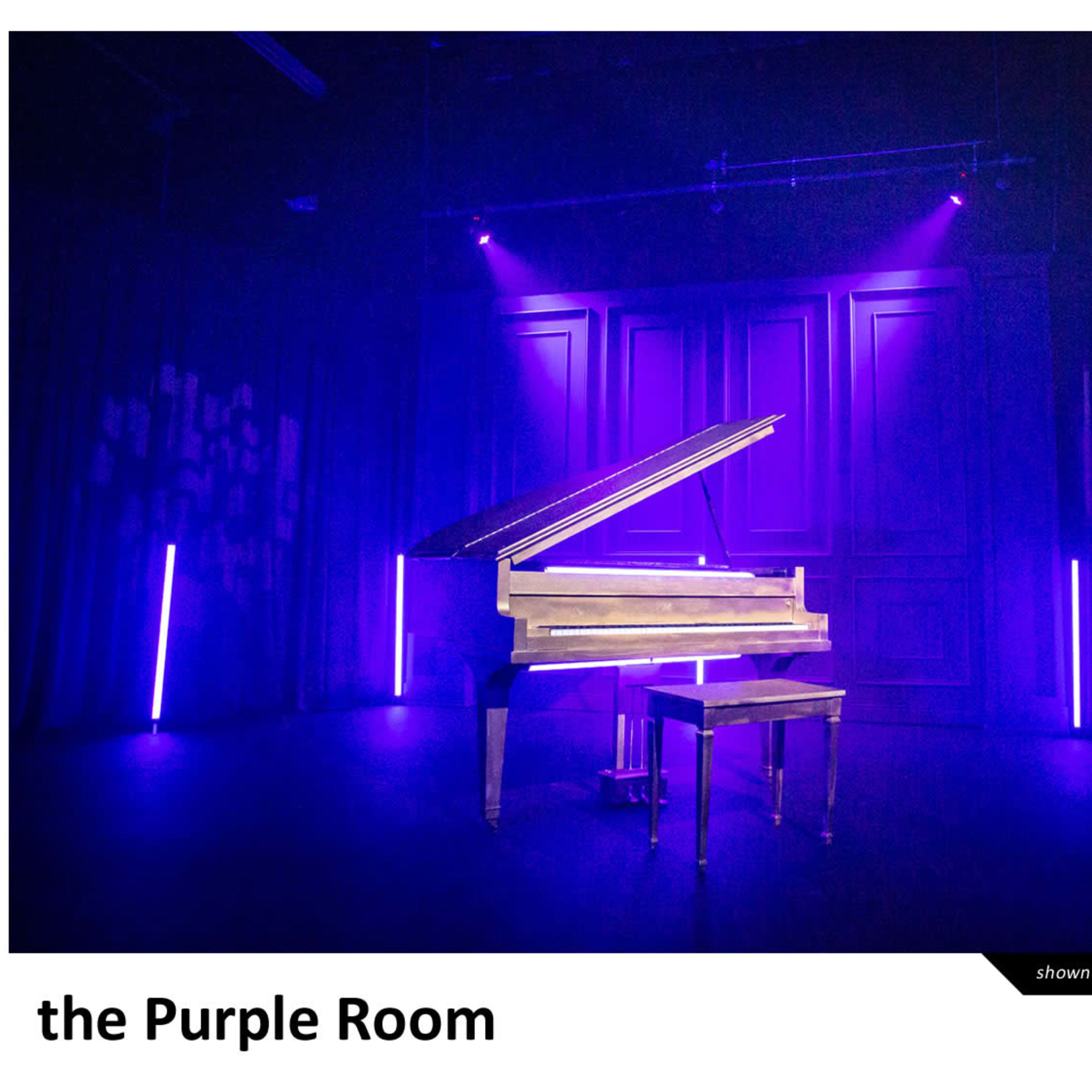 A grand piano illuminated by colorful stage lights in a theater setting.