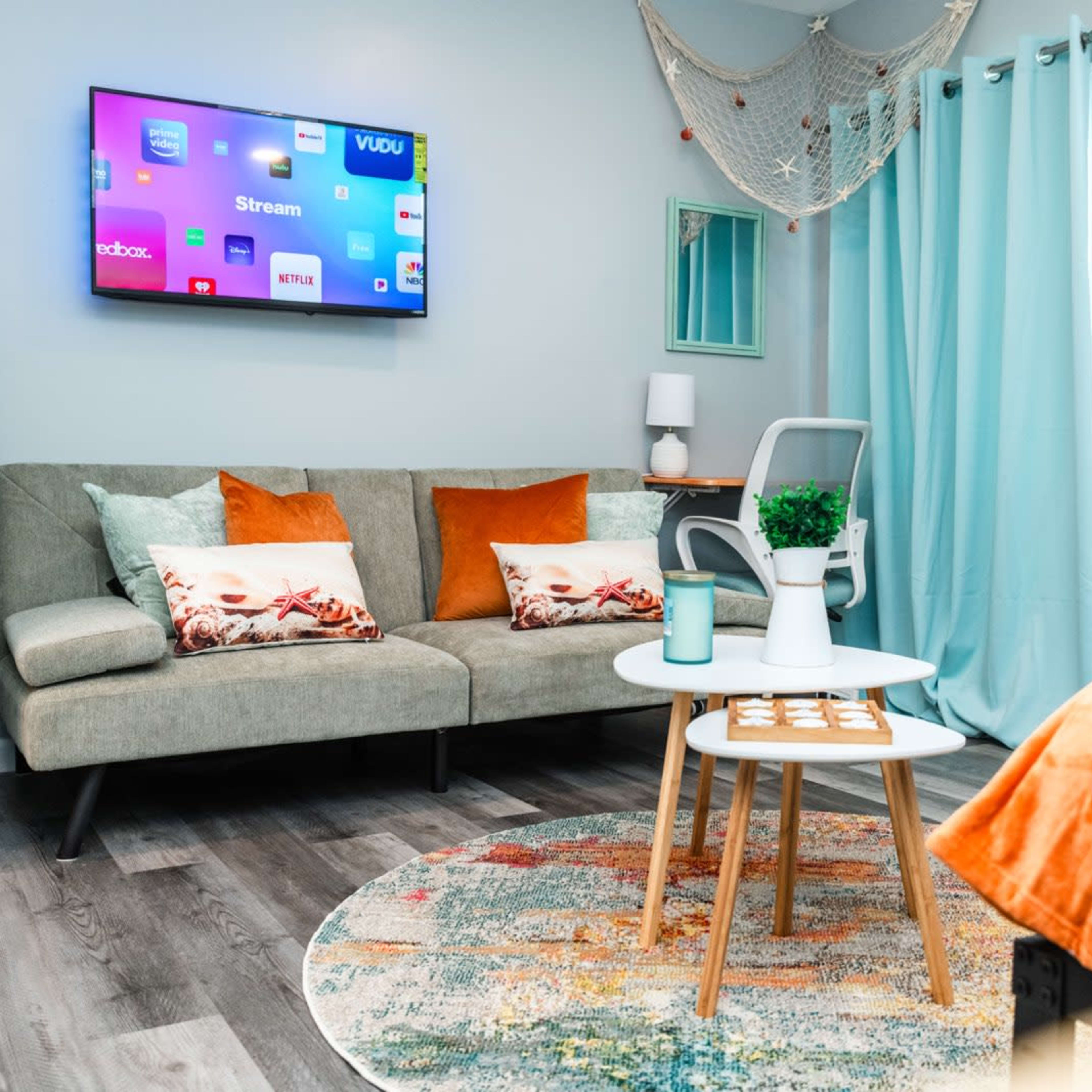 A cozy living space with a gray sofa, a small round coffee table, and a wall-mounted TV displaying streaming apps.