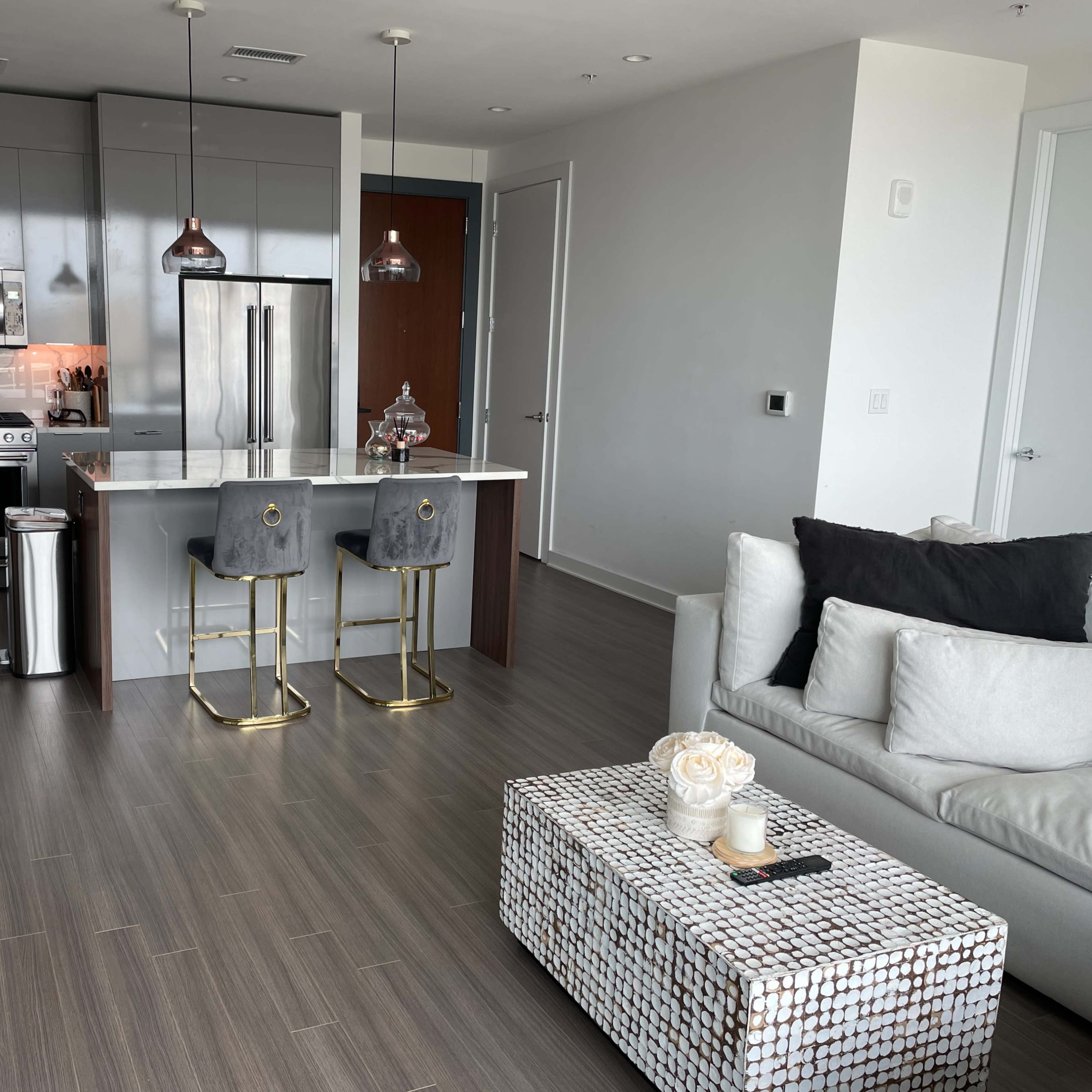 A modern kitchen and living area feature a sleek design with gray cabinets, stainless steel appliances, and a decorative coffee table.