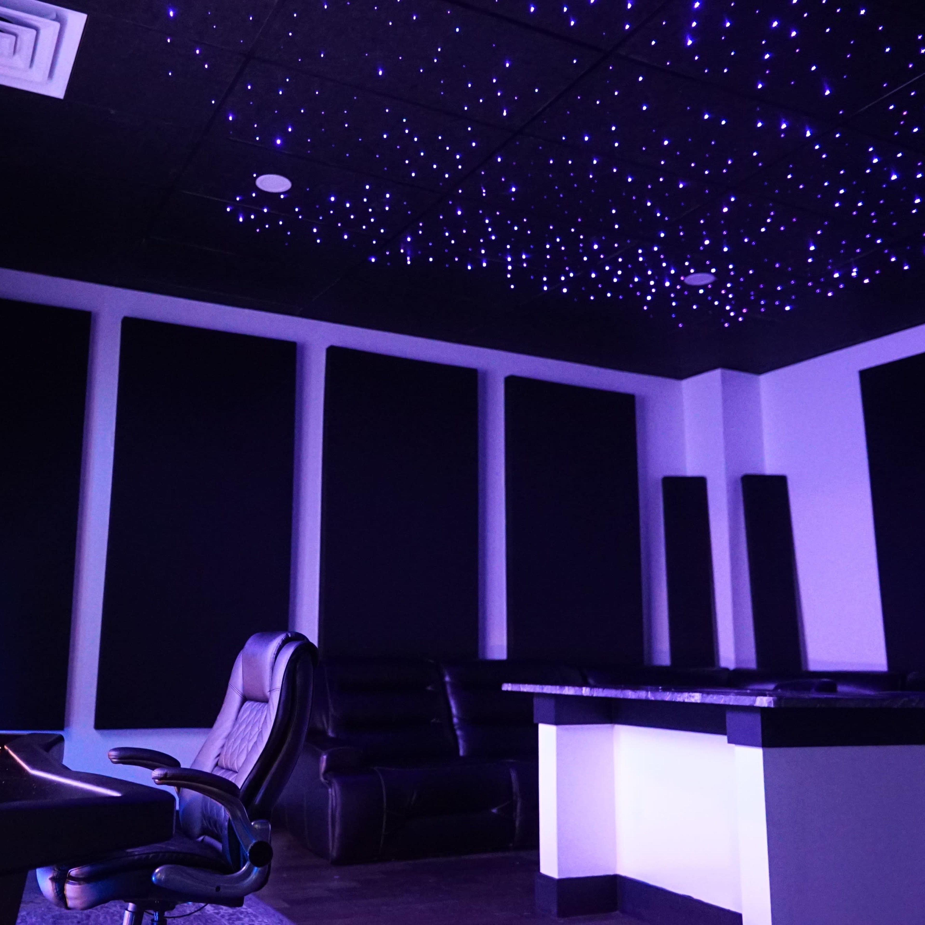 A soundproof room with dark walls, a starry ceiling, a desk with monitoring equipment, and a large comfortable chair.