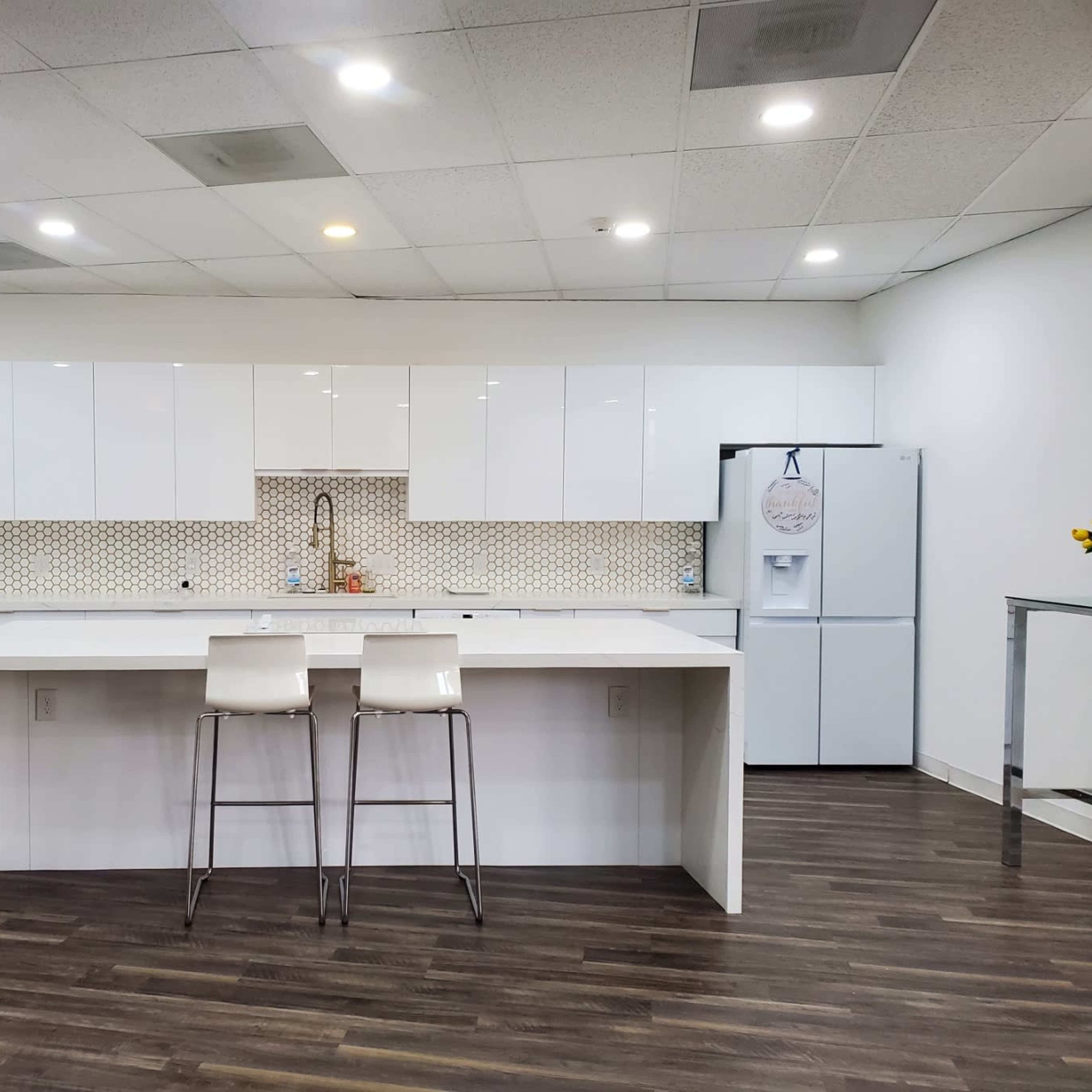 A modern kitchen features white cabinetry, a patterned backsplash, and a central island with two stools.