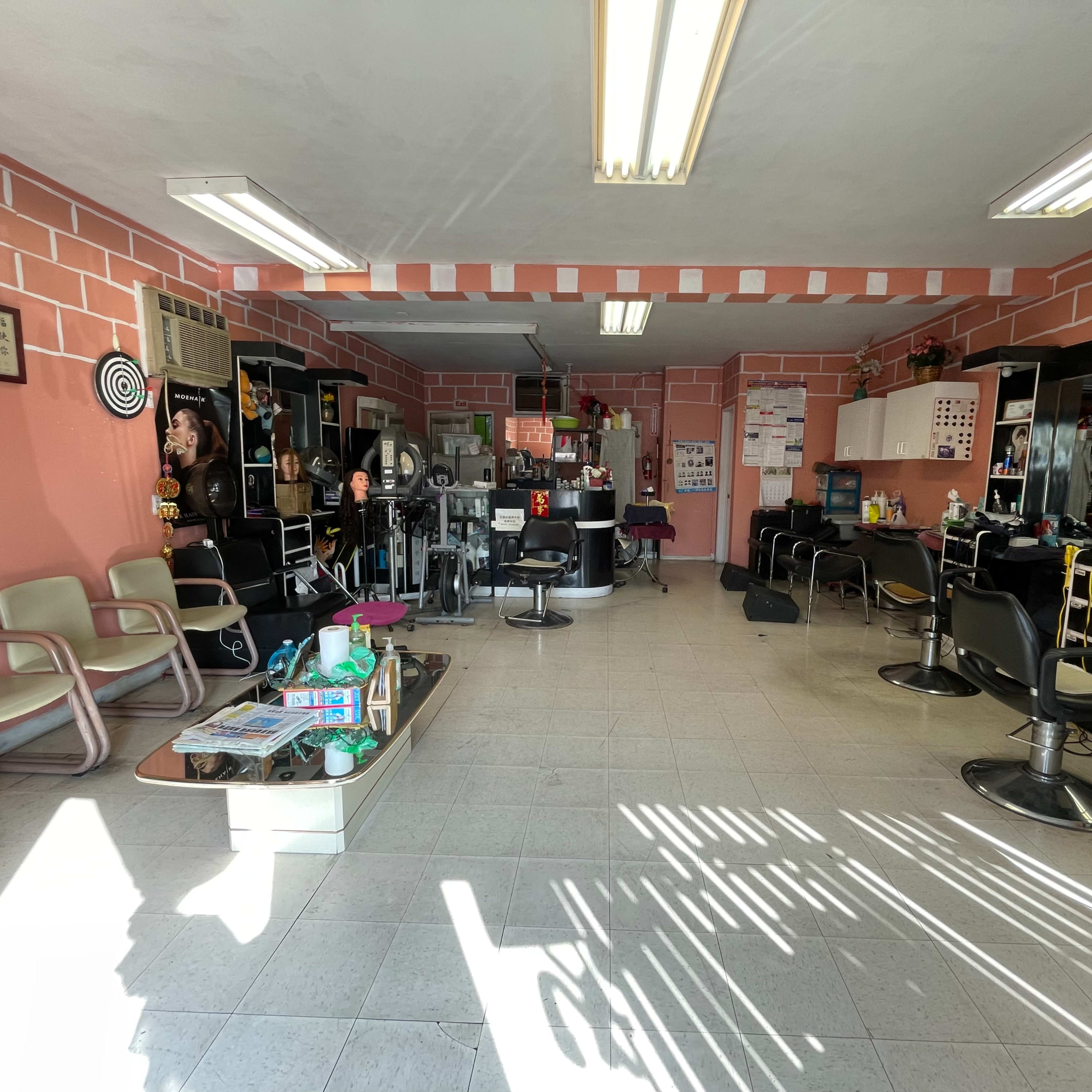 The interior of a barbershop with several chairs, styling stations, and a bright pink wall.