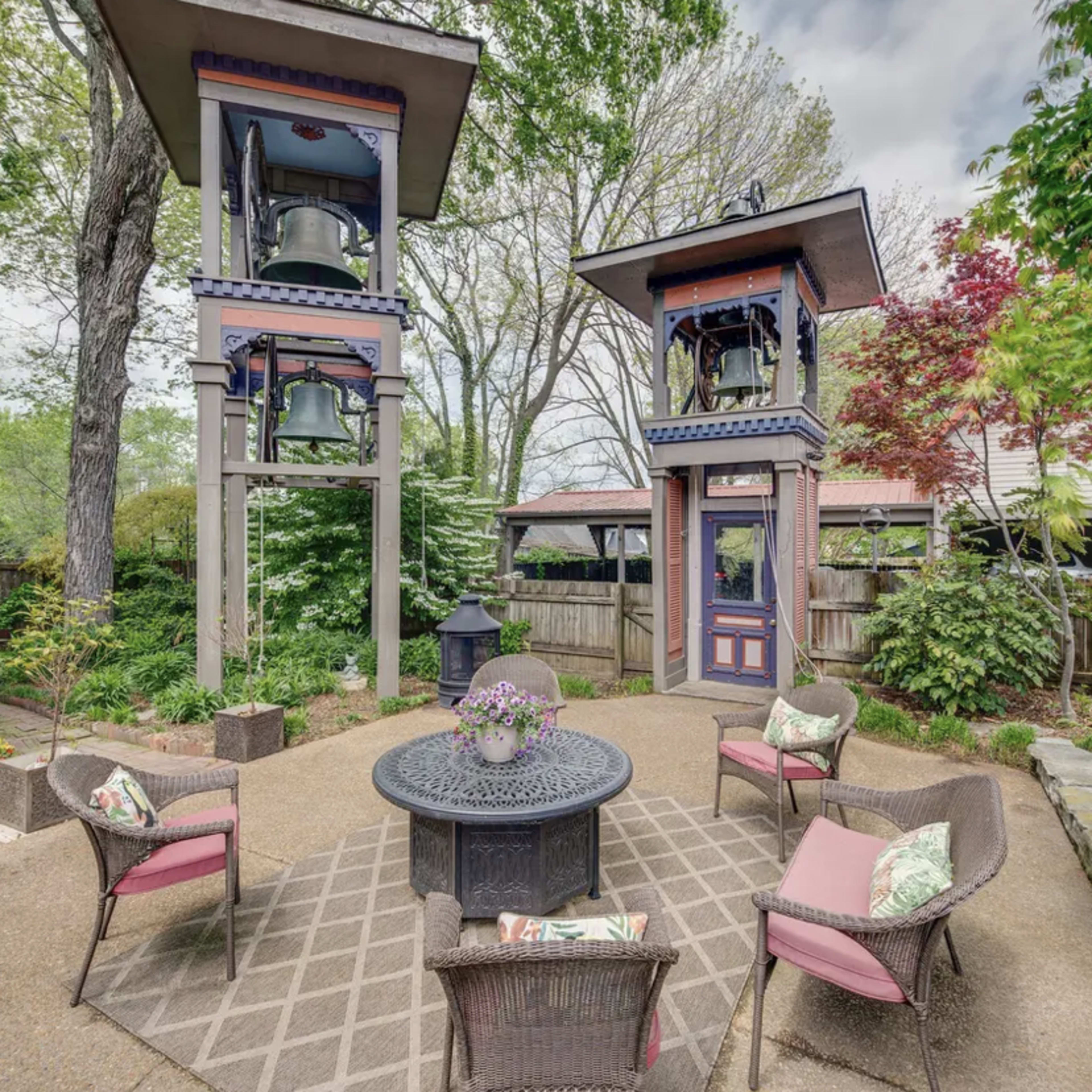 A garden with two tall bell towers flanking a circular seating area with a table and chairs.