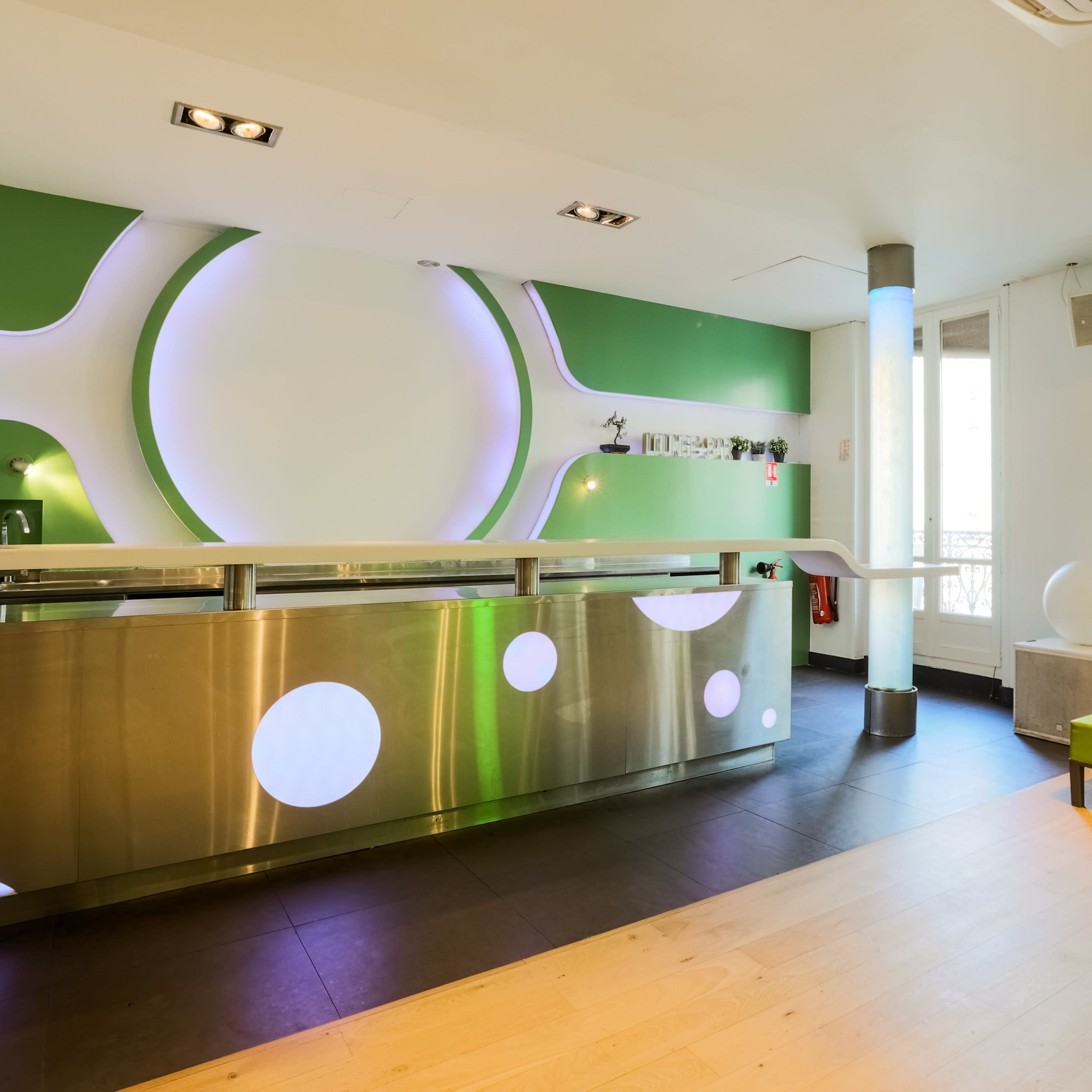 A modern, minimalist reception area with a metallic front desk and green accent walls.