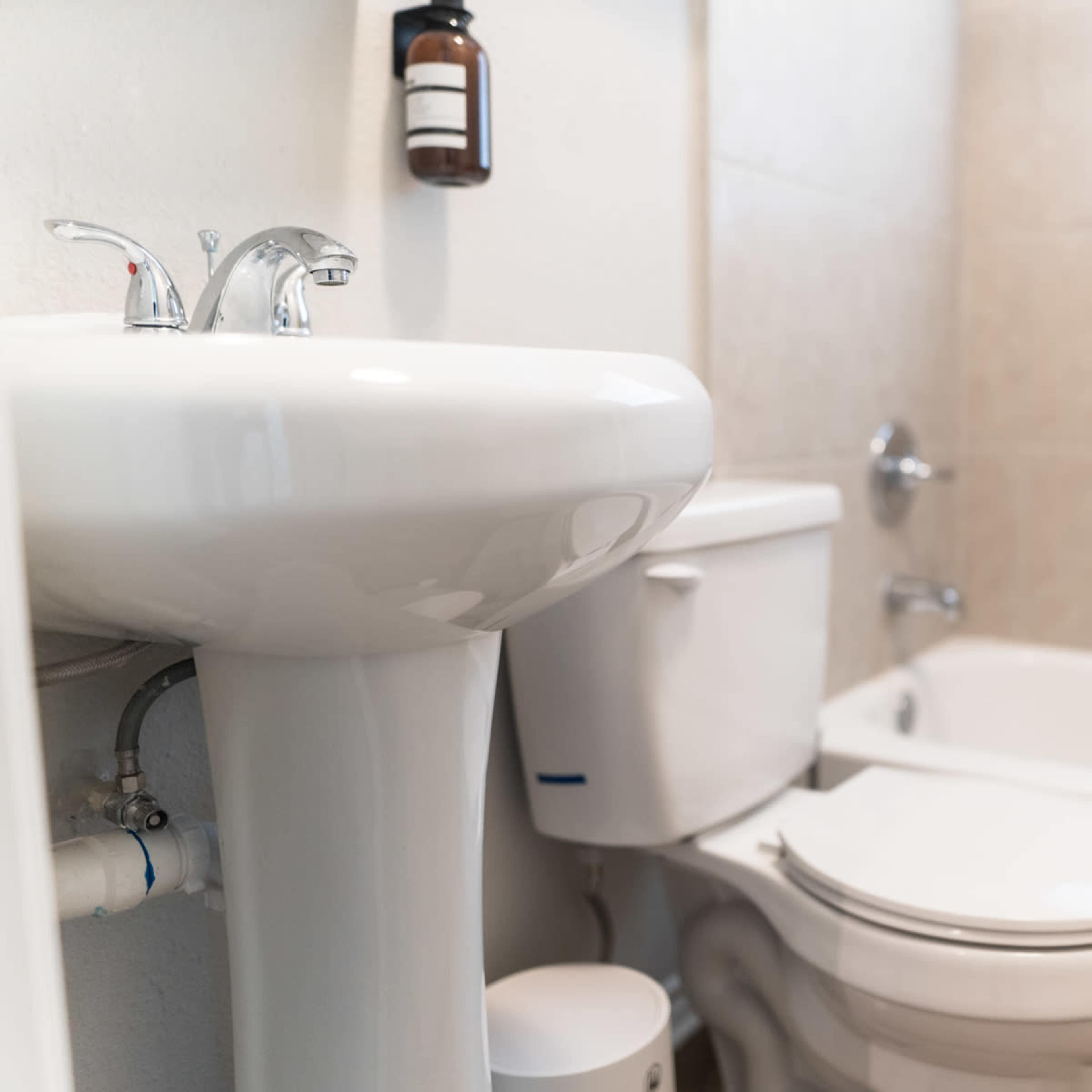 A bathroom with a white sink and toilet next to a bathtub, featuring a window for natural light.