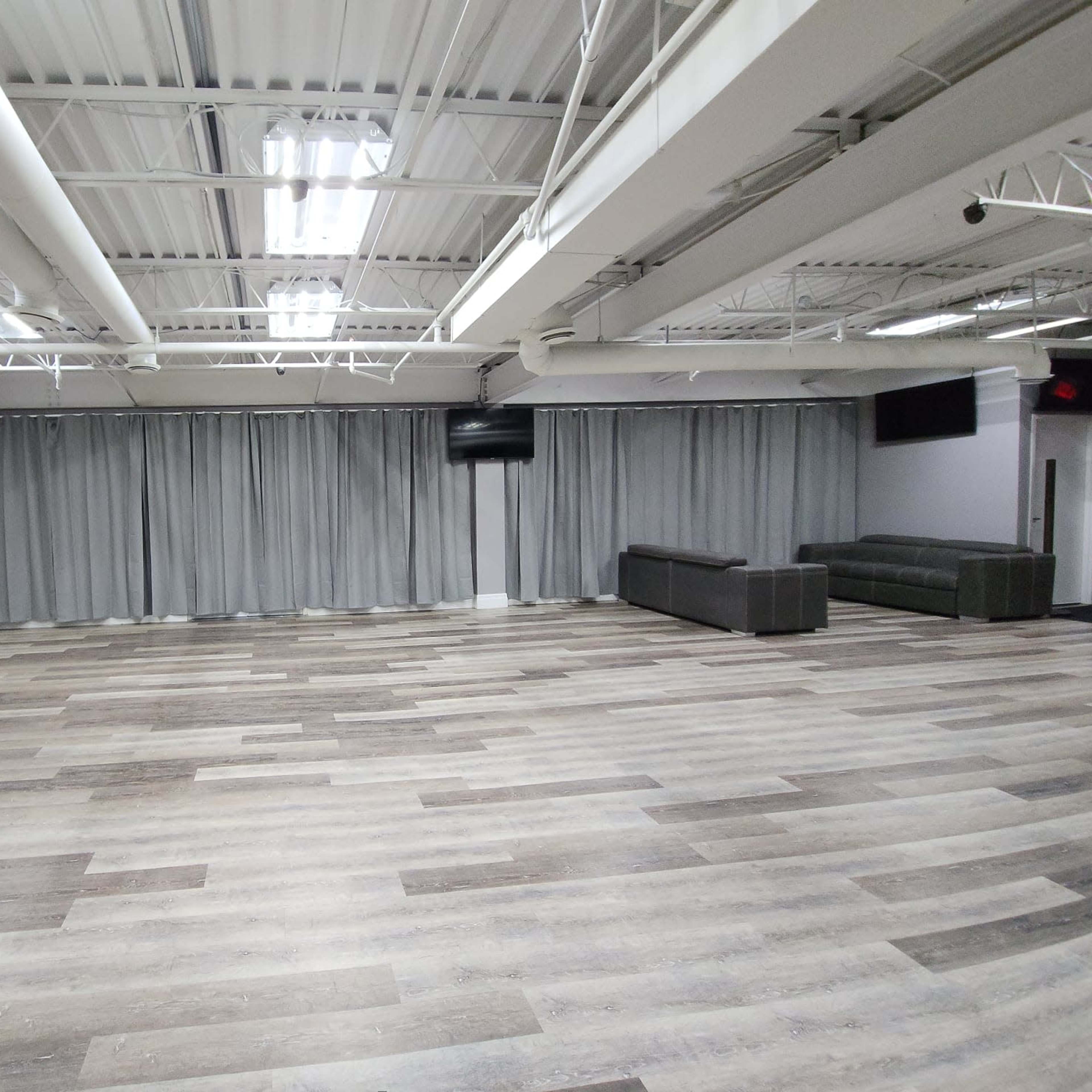 A spacious indoor area with gray curtains, a sleek floor, and minimal furniture including a table and chairs.