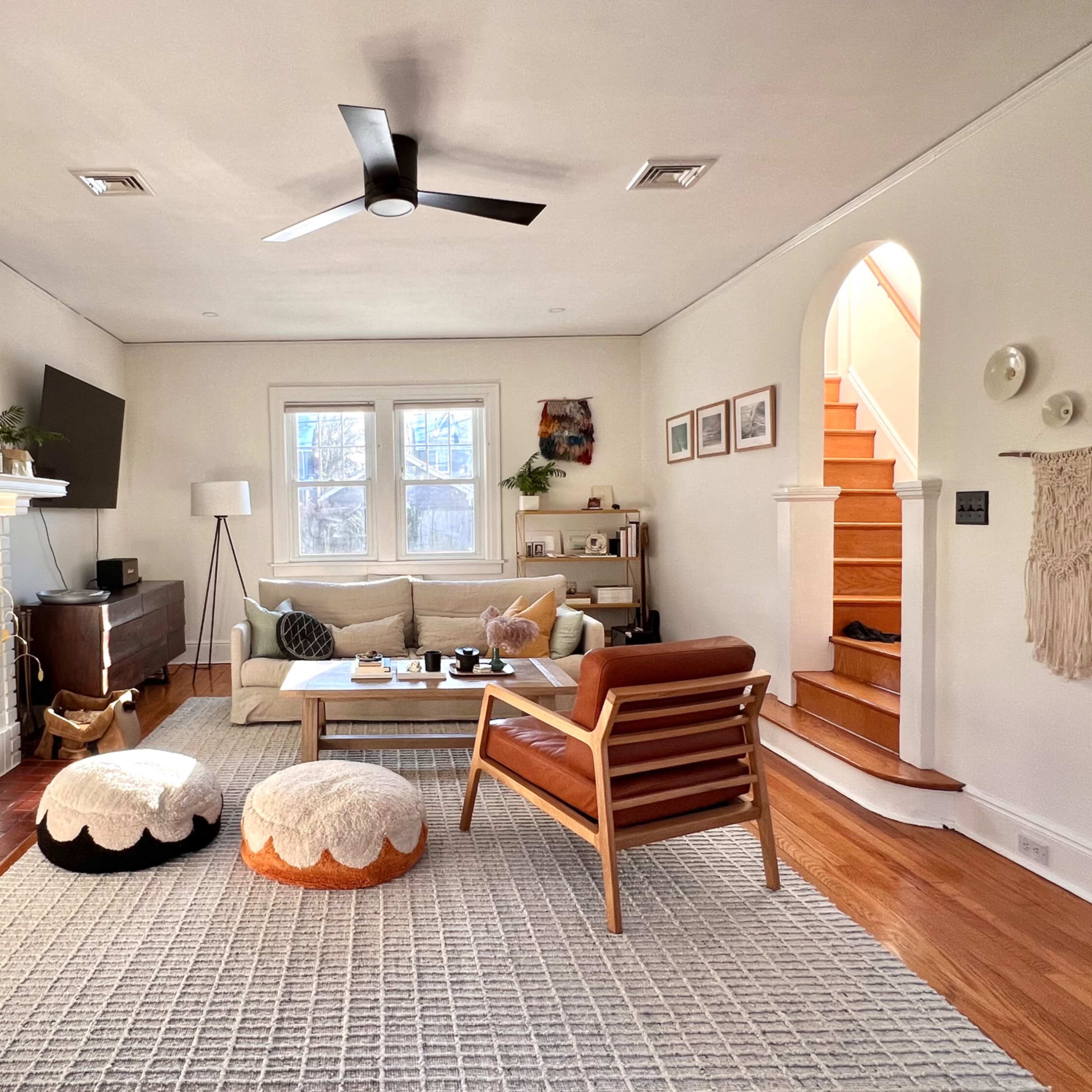 The living room features a white brick fireplace, a comfortable sofa, a wooden coffee table, and a staircase leading to an upper level.