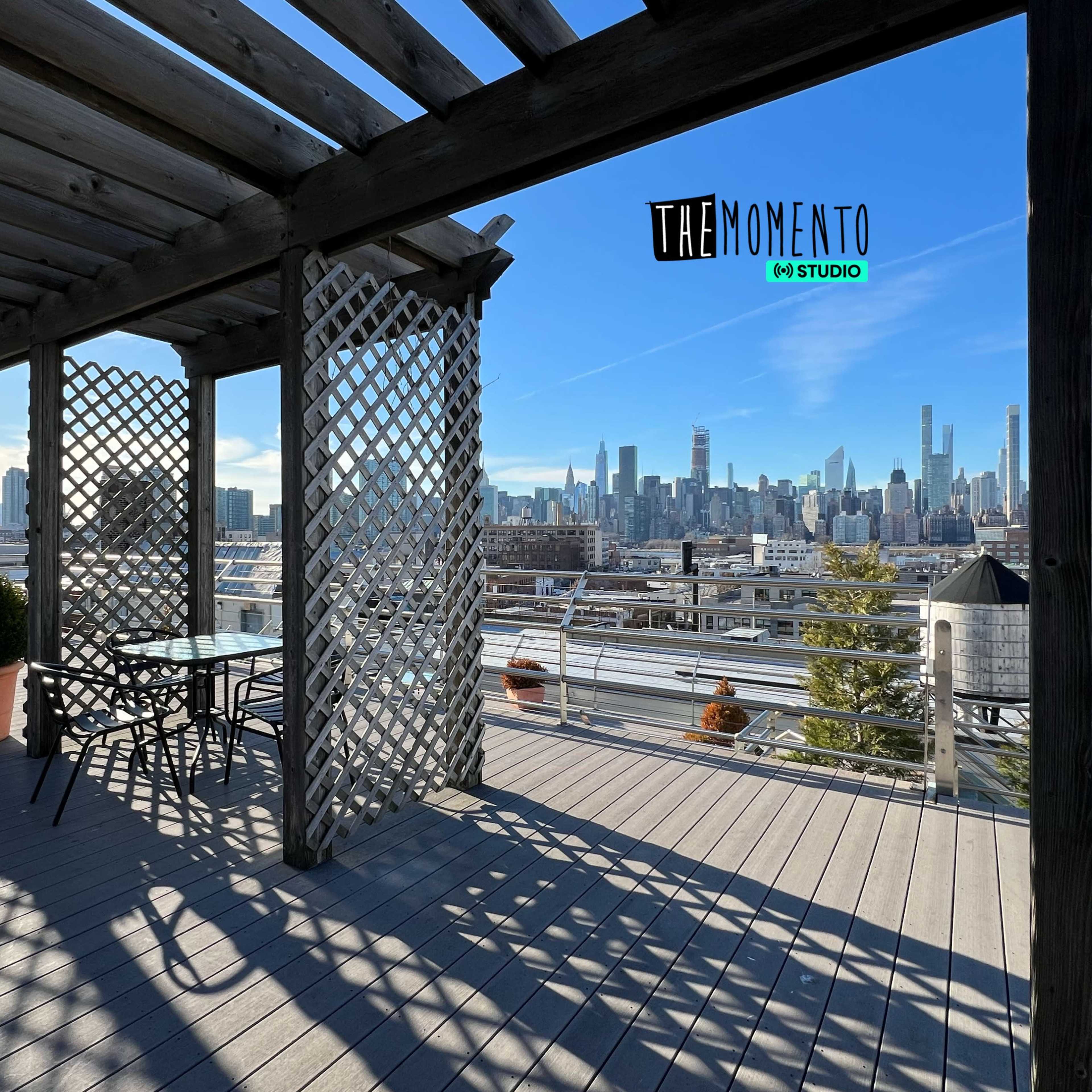 A timber-framed terrace with a lattice design overlooks a city skyline against a clear blue sky.