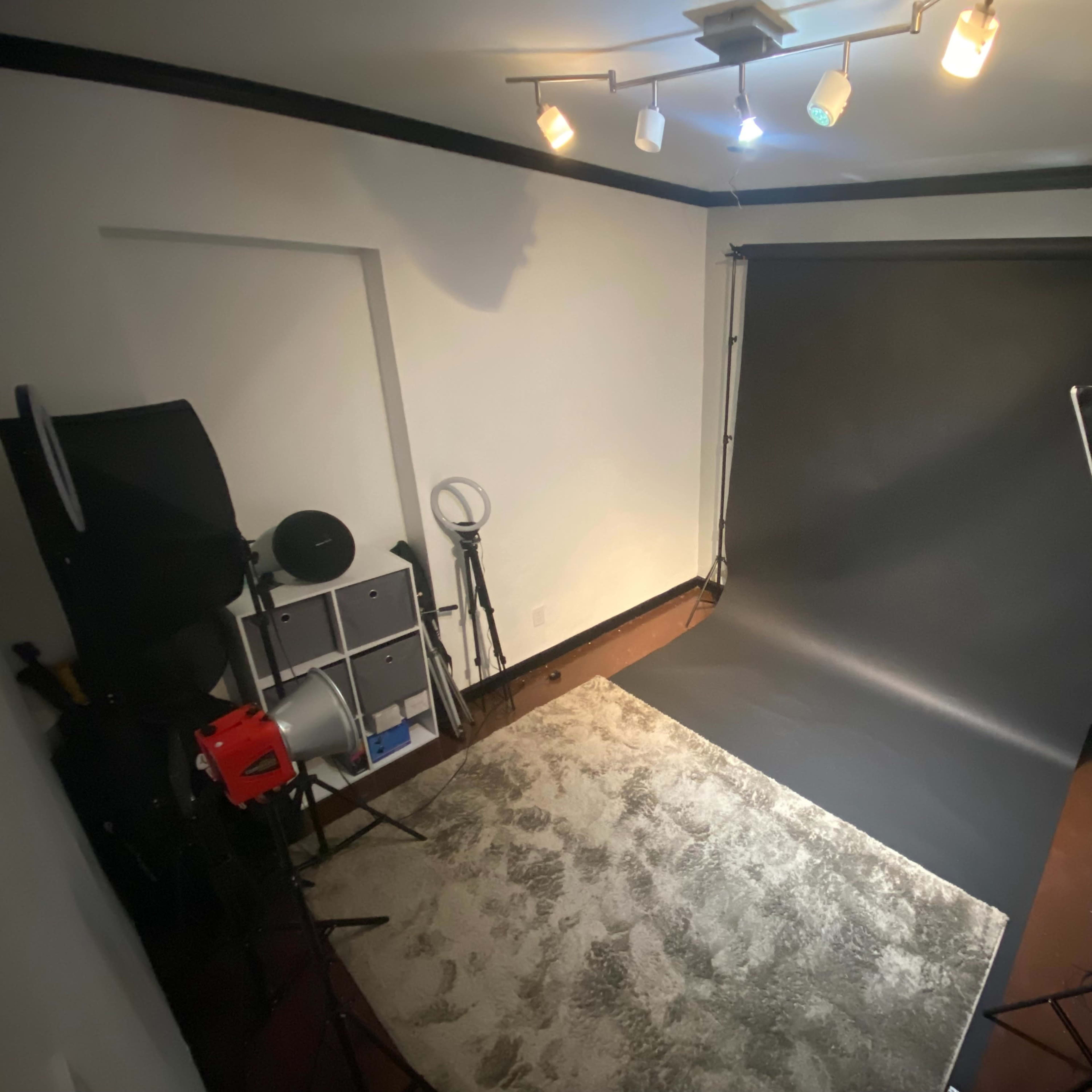A photography studio with a dark backdrop, lighting equipment, and a carpeted area.