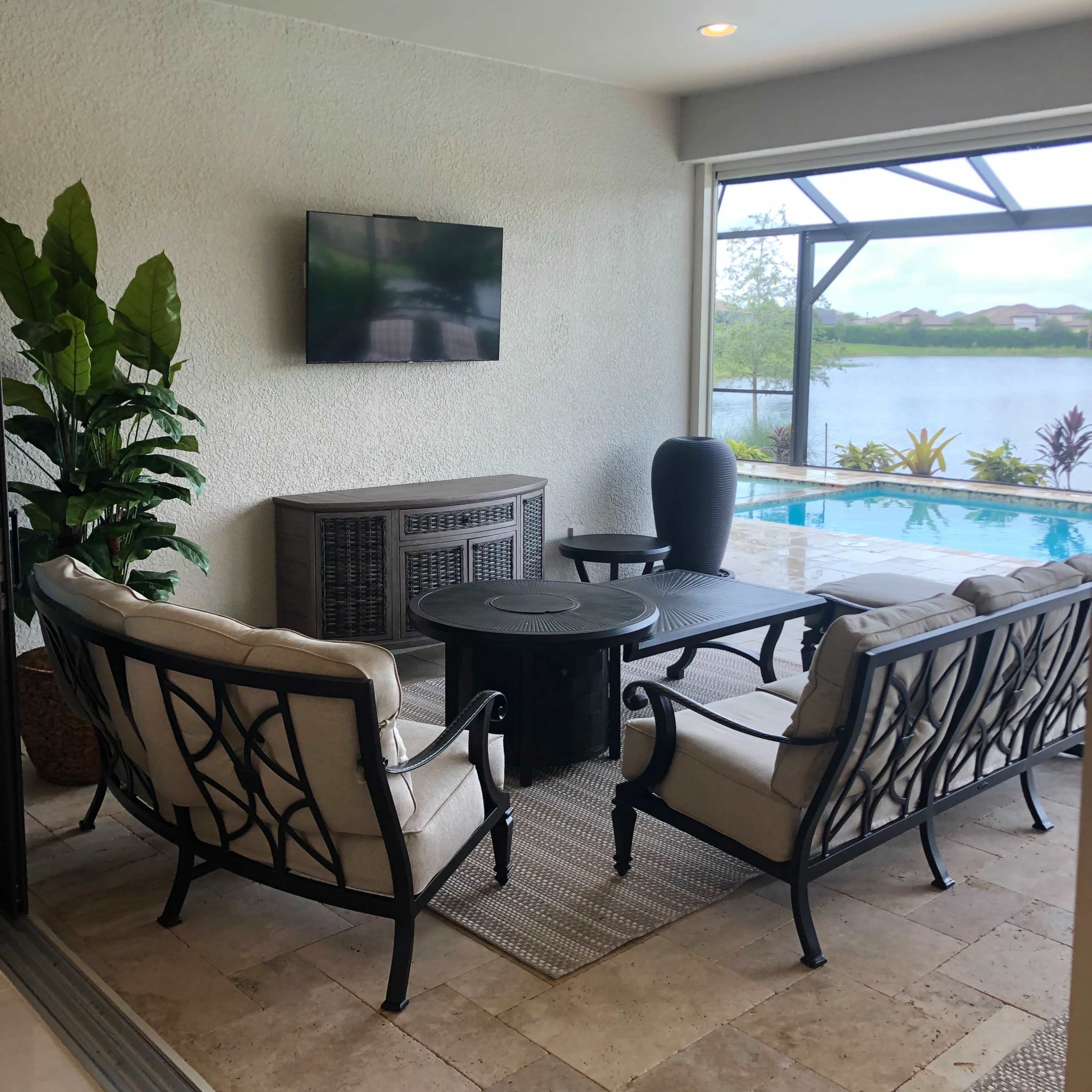 A cozy seating area with two chairs and a table overlooks a pool and a scenic view through glass doors.