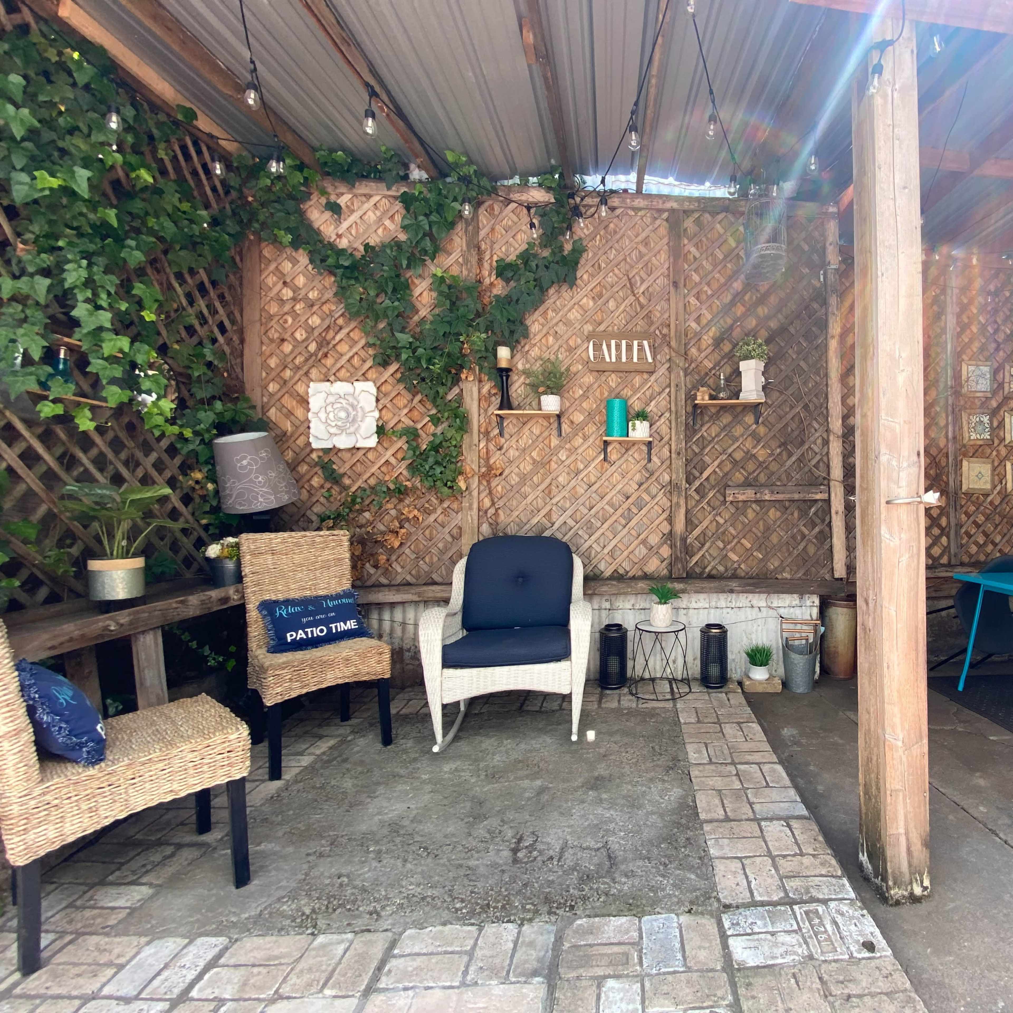A cozy outdoor patio area with wooden lattice, potted plants, and a blue table surrounded by chairs.