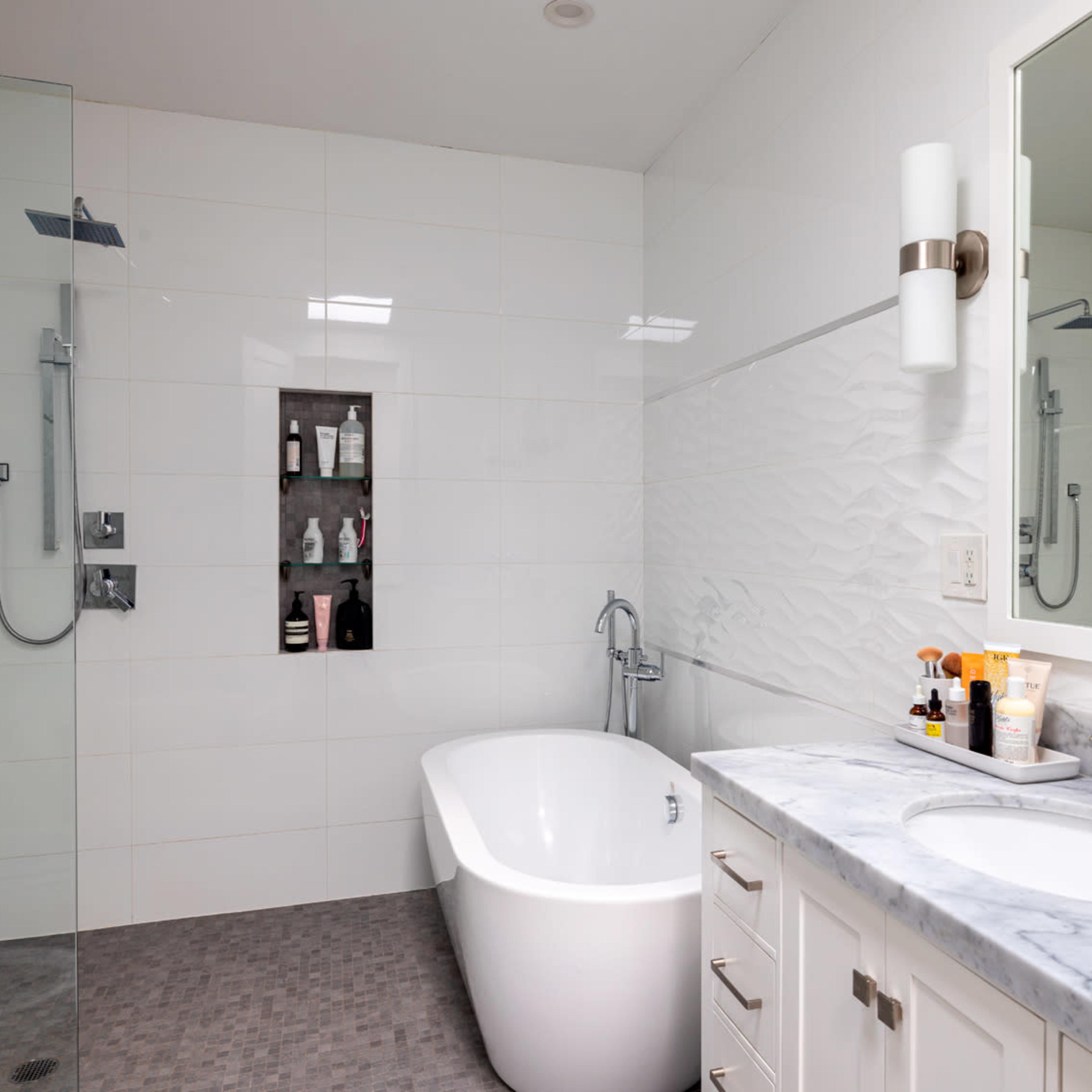 A modern bathroom with a walk-in shower, freestanding bathtub, and a marble-topped vanity with two sinks.