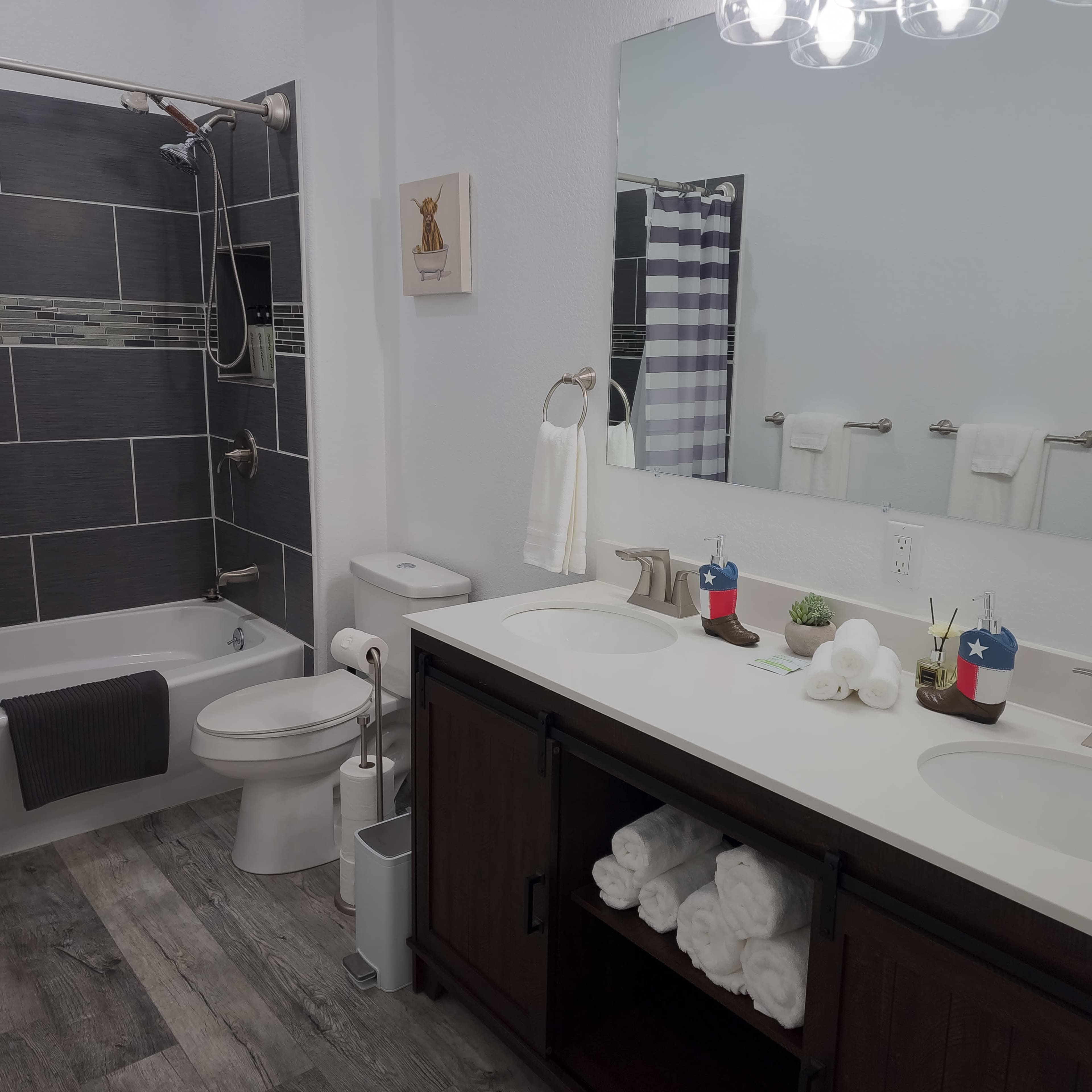 A modern bathroom featuring a tub and shower combination, a double sink vanity with towels, and decorative elements.