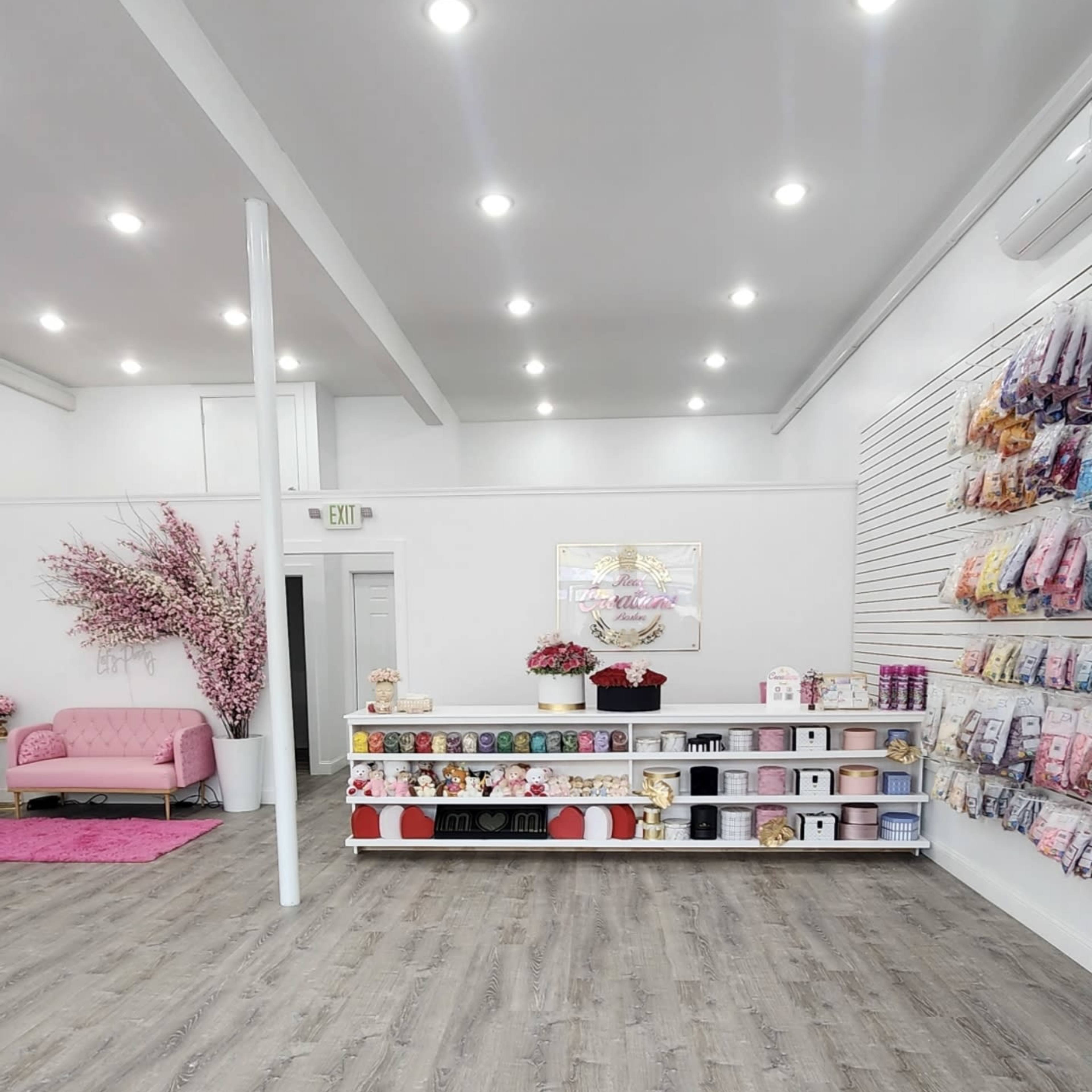 A neatly arranged boutique with shelves displaying various products, a pink couch, and decorative floral accents.