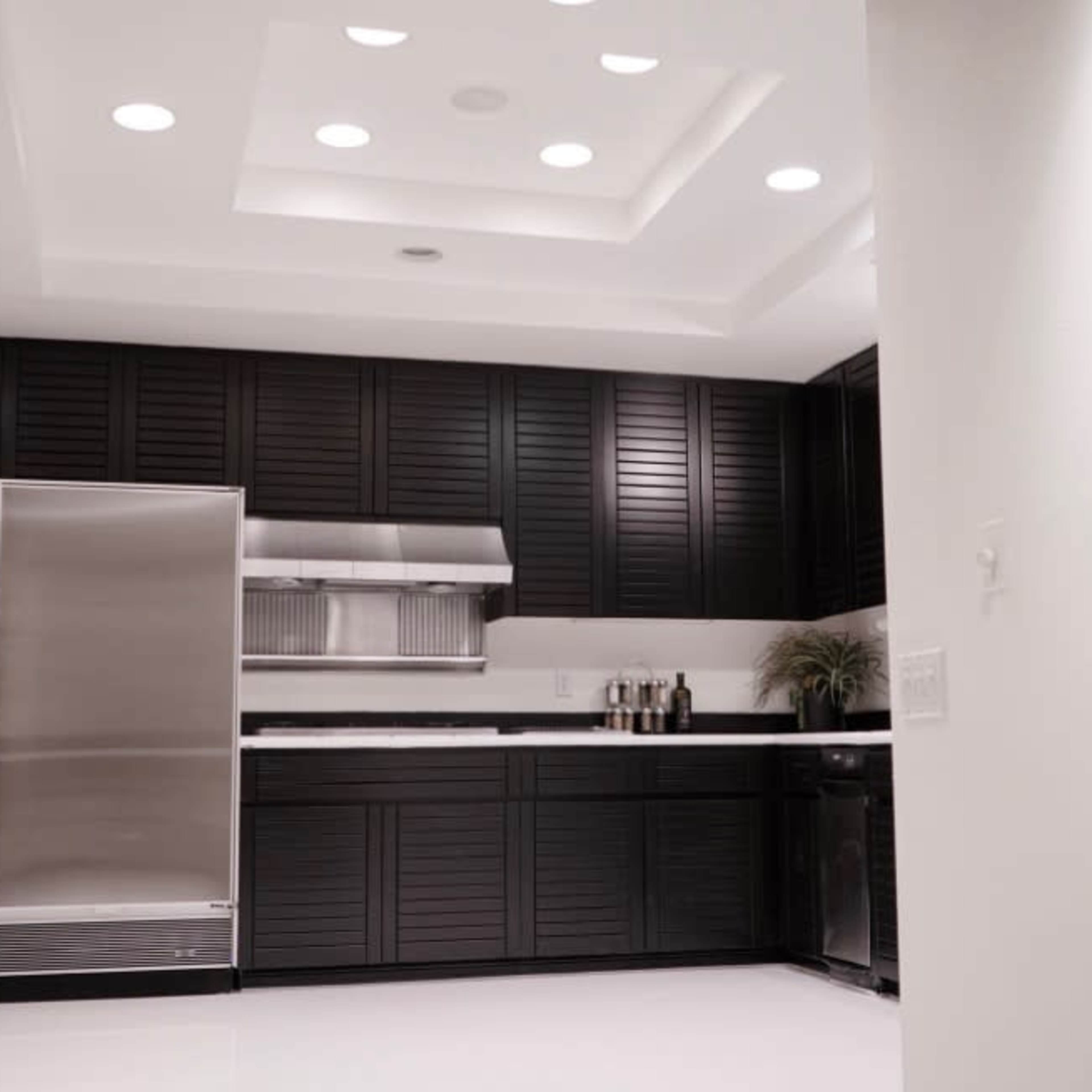 A modern kitchen features black cabinetry, stainless steel appliances, and recessed lighting in a sleek design.