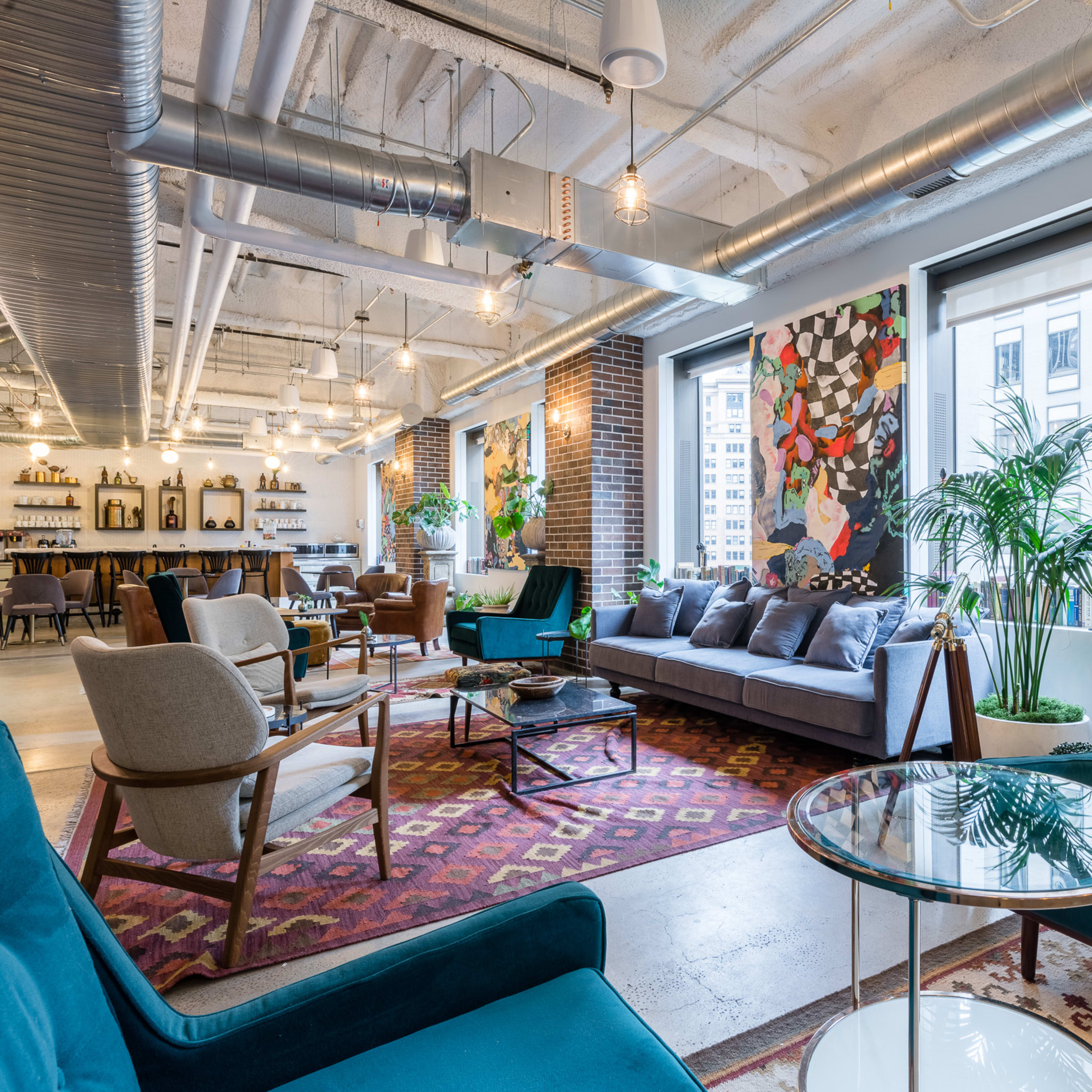 A modern, open lounge area with comfortable seating, large windows, and decorative artwork on the walls.