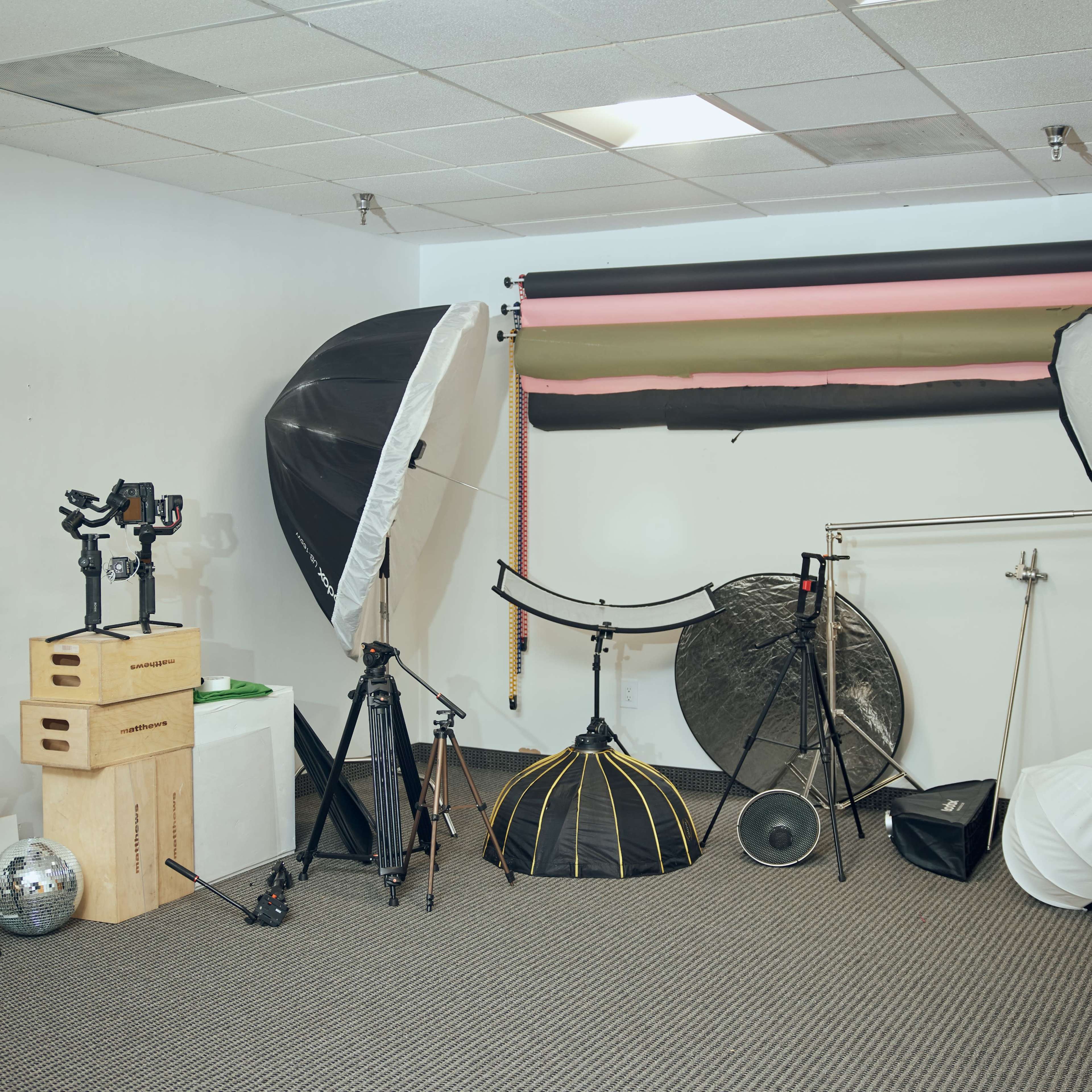 A photography studio filled with various lighting equipment, backdrops, tripods, and reflectors.