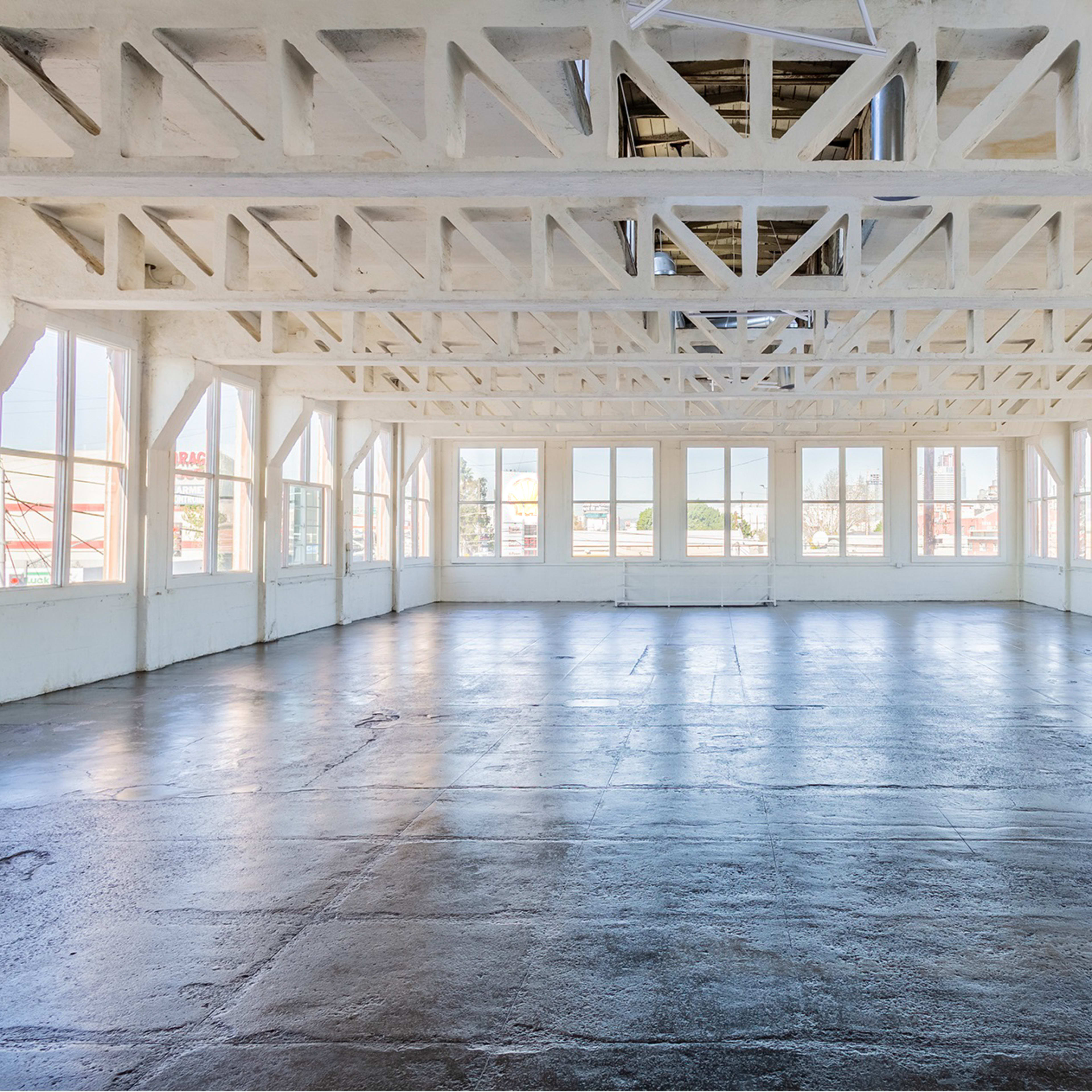 A spacious, well-lit room with large windows and exposed wooden beams.
