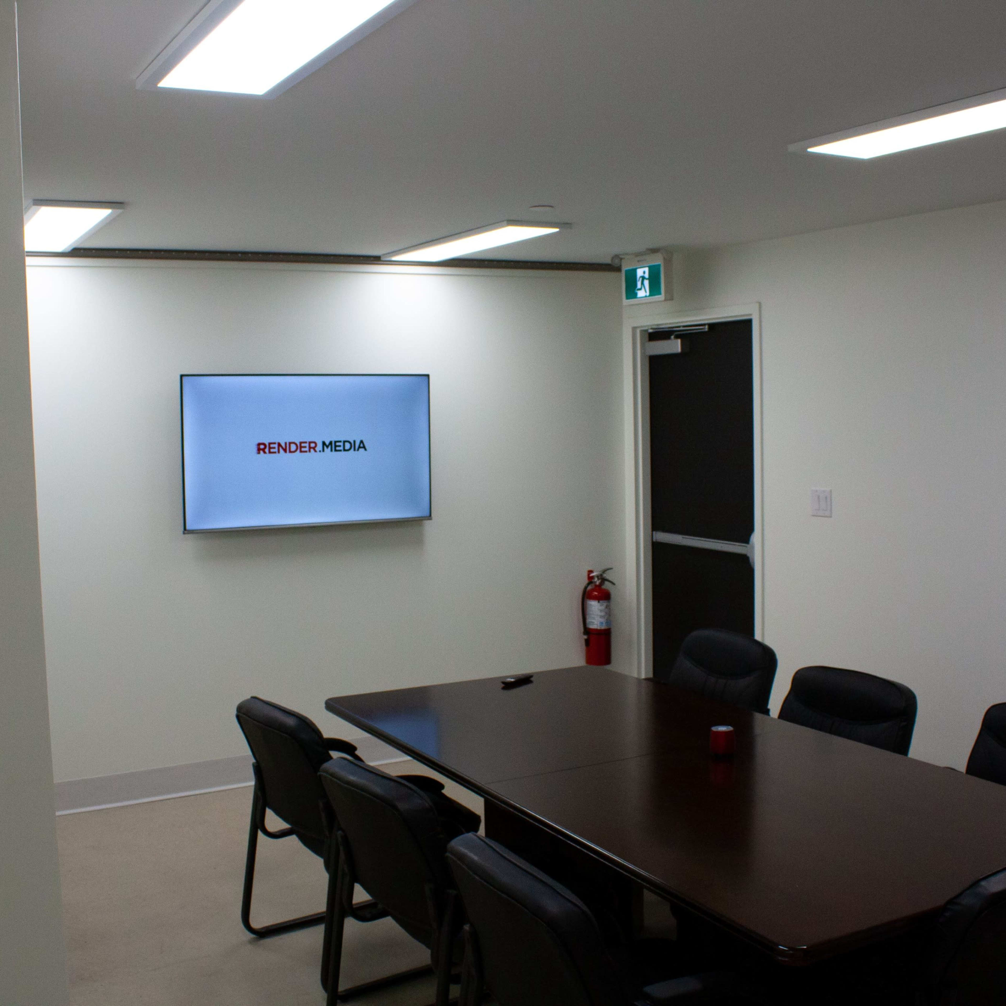 A conference room features a long wooden table surrounded by black chairs, with a screen displaying the logo "RENDER MEDIA" on the wall.