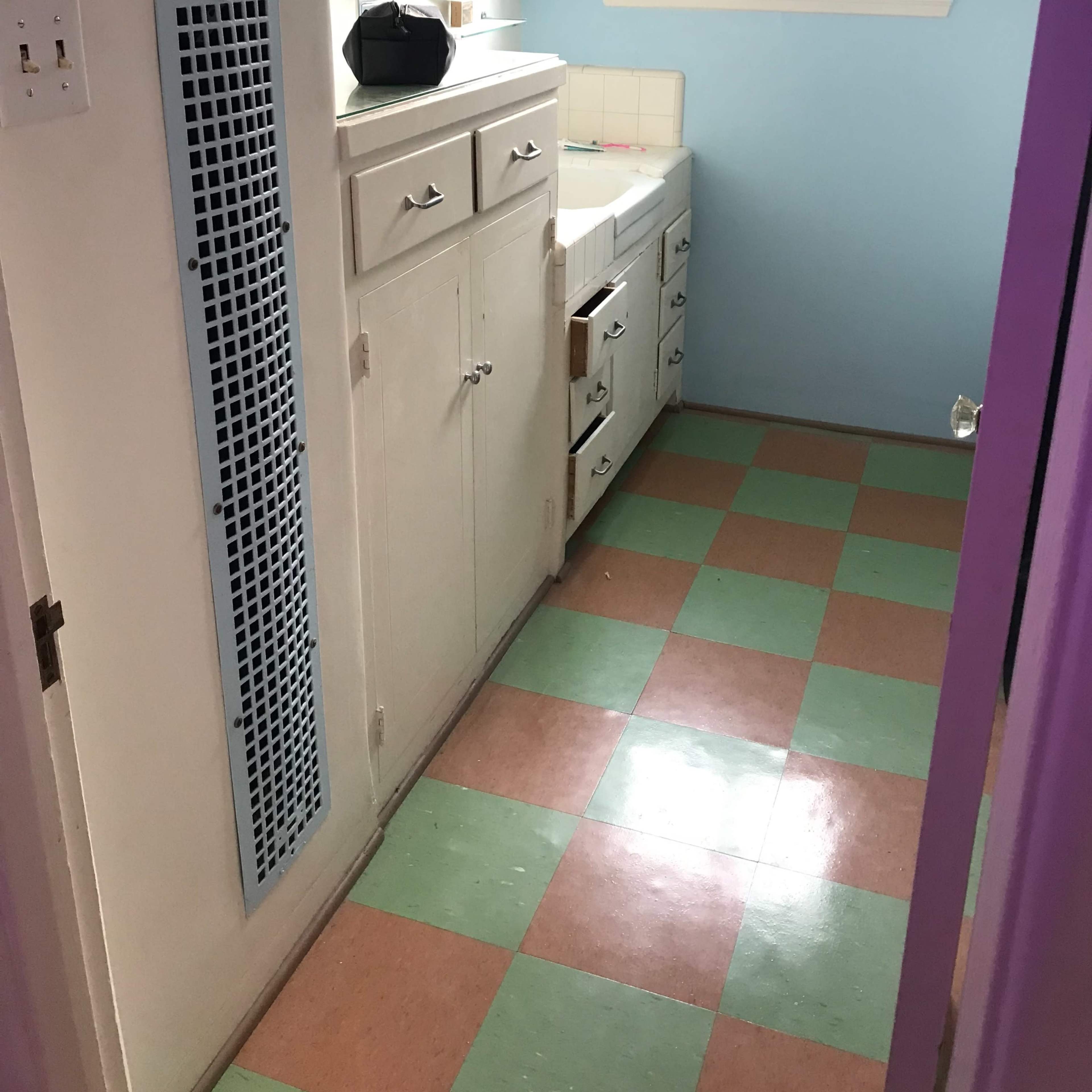 A small hallway with a colored tiled floor, a window providing natural light, and storage cabinets along one wall.