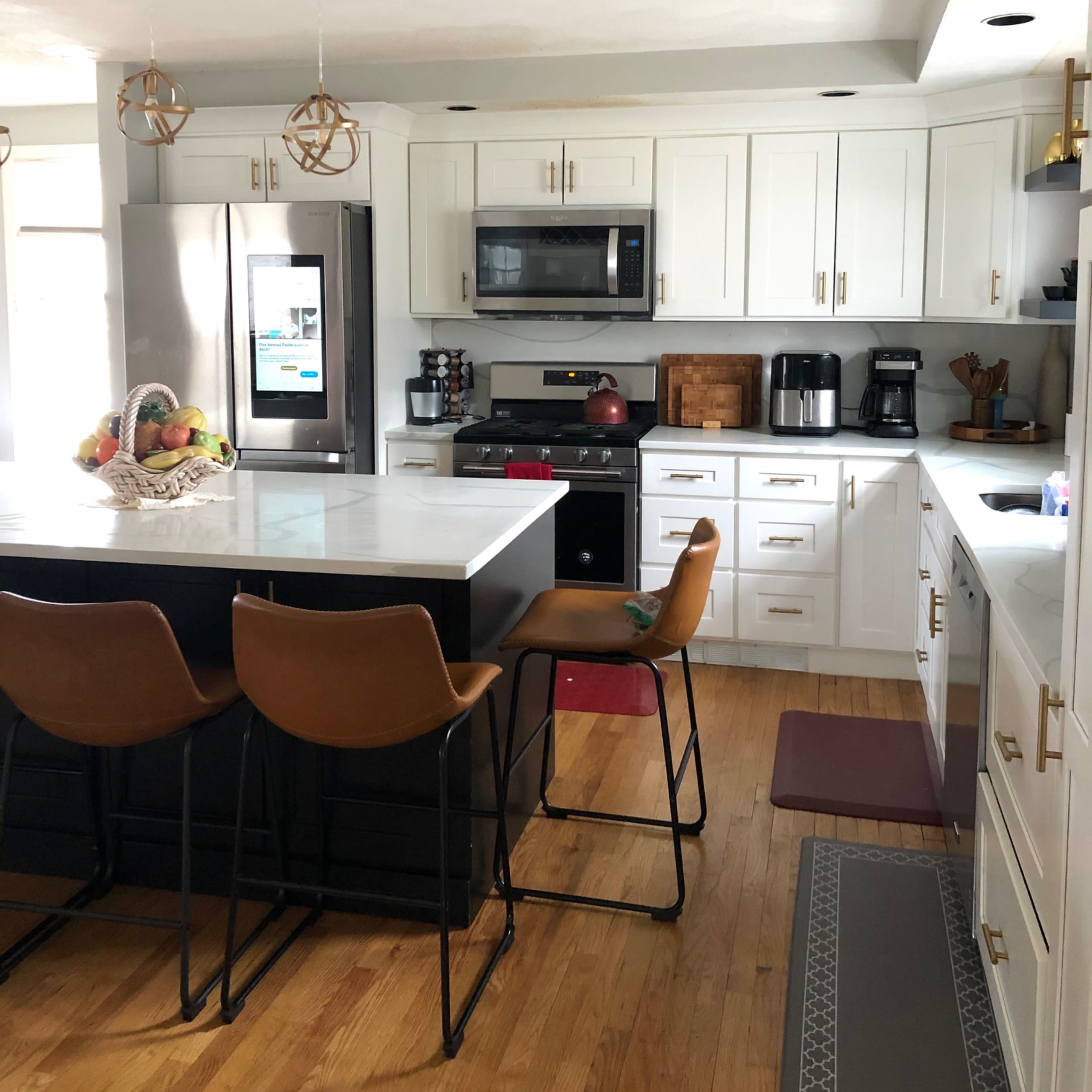 A modern kitchen featuring a large island with seating, white cabinetry, and stainless steel appliances.