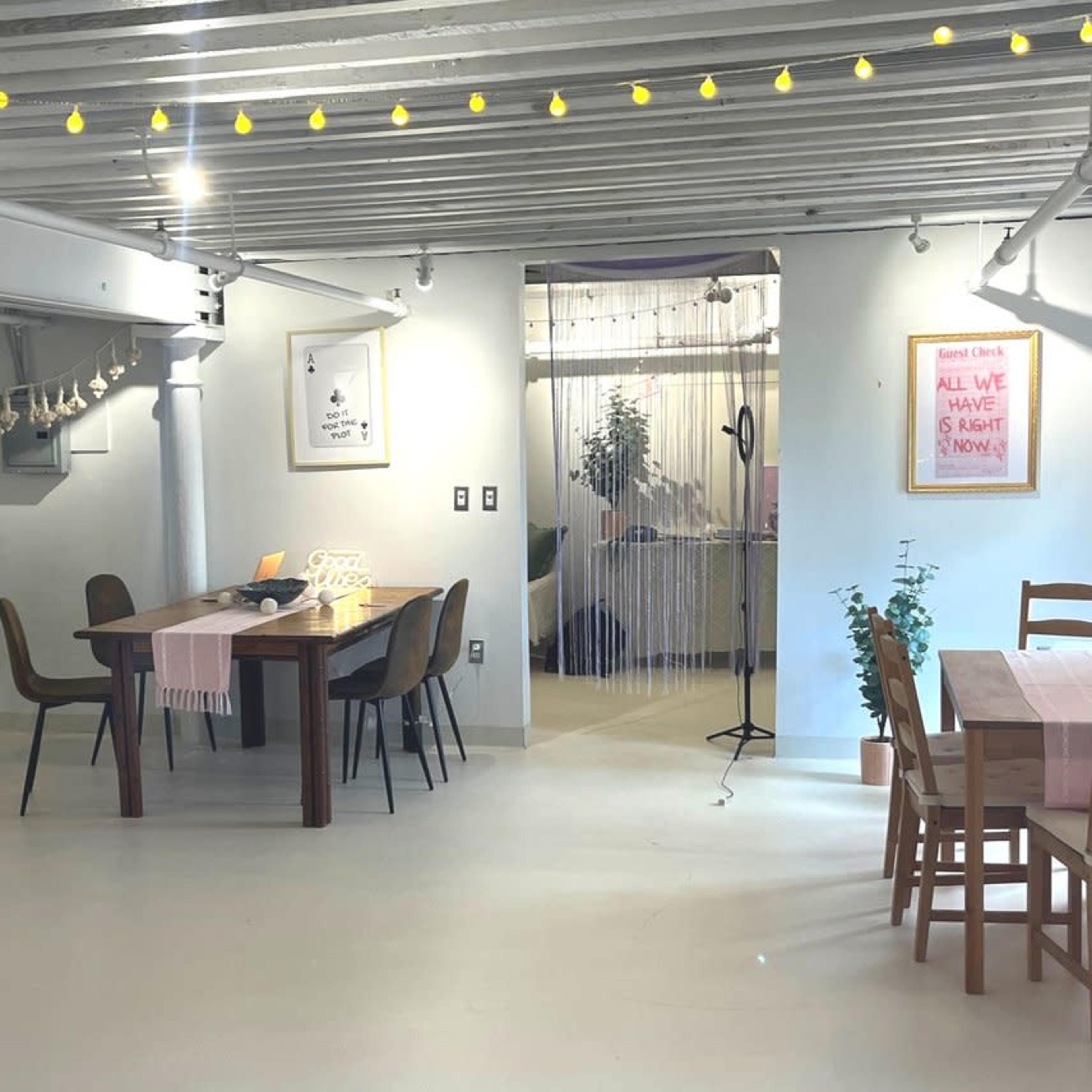 A spacious, modern interior featuring a dining area with tables and chairs, a cozy seating corner, and decorative plants.