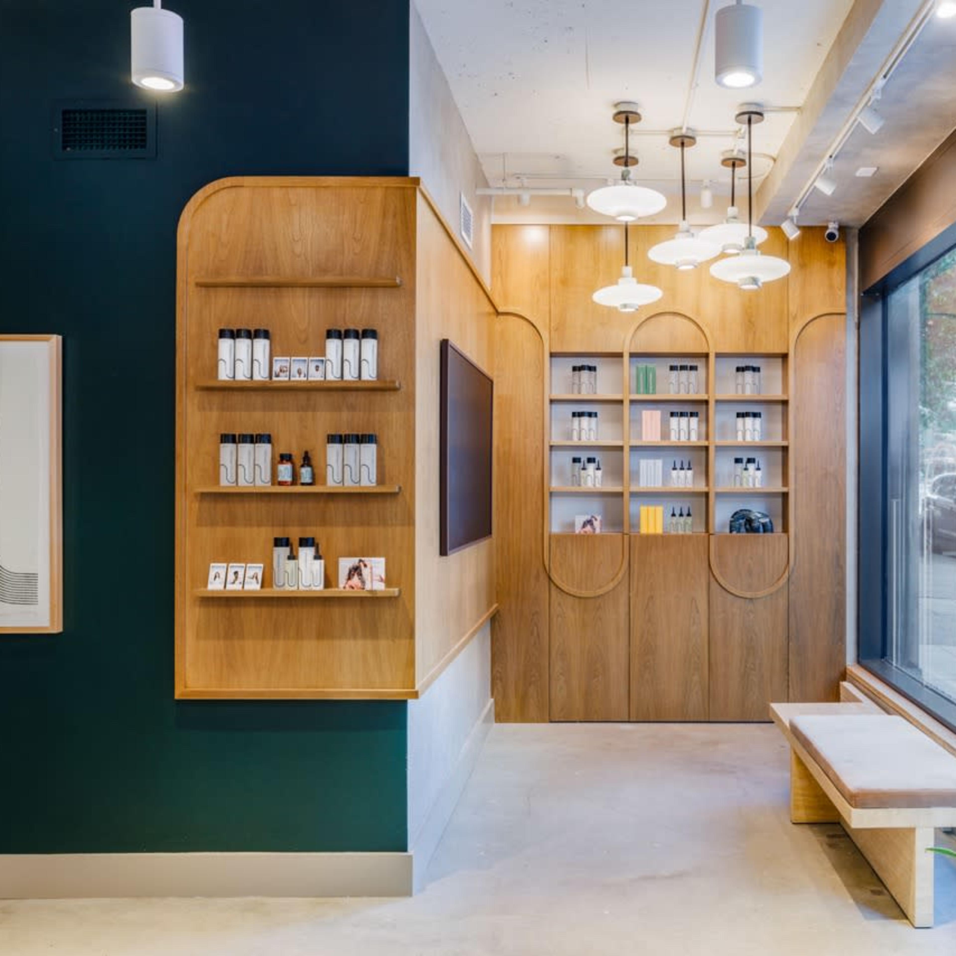 A modern interior of a skincare shop featuring wooden shelves with products, a large window, and pendant lights.