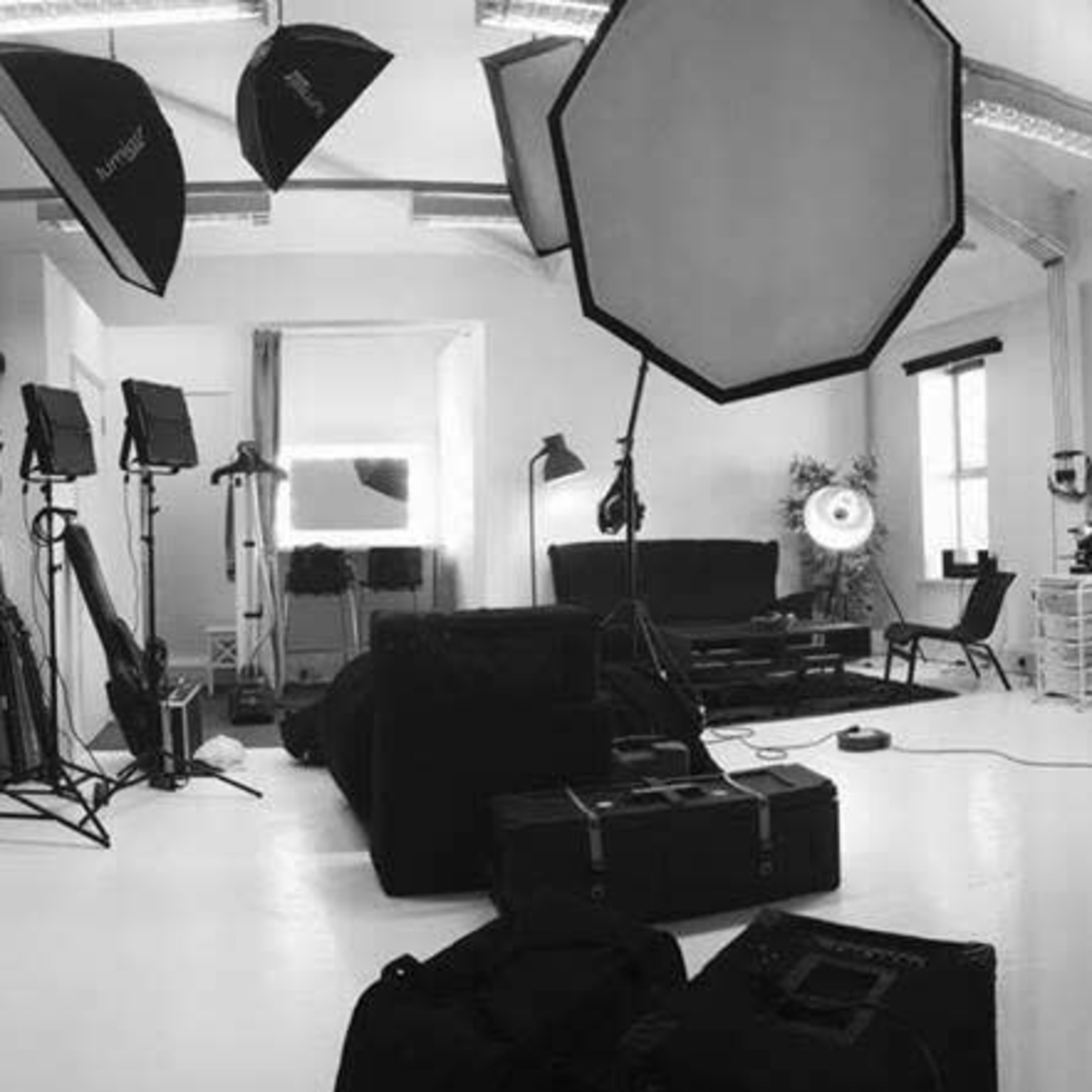 A photography studio equipped with various lights, backdrops, and furniture arranged in a spacious white room.
