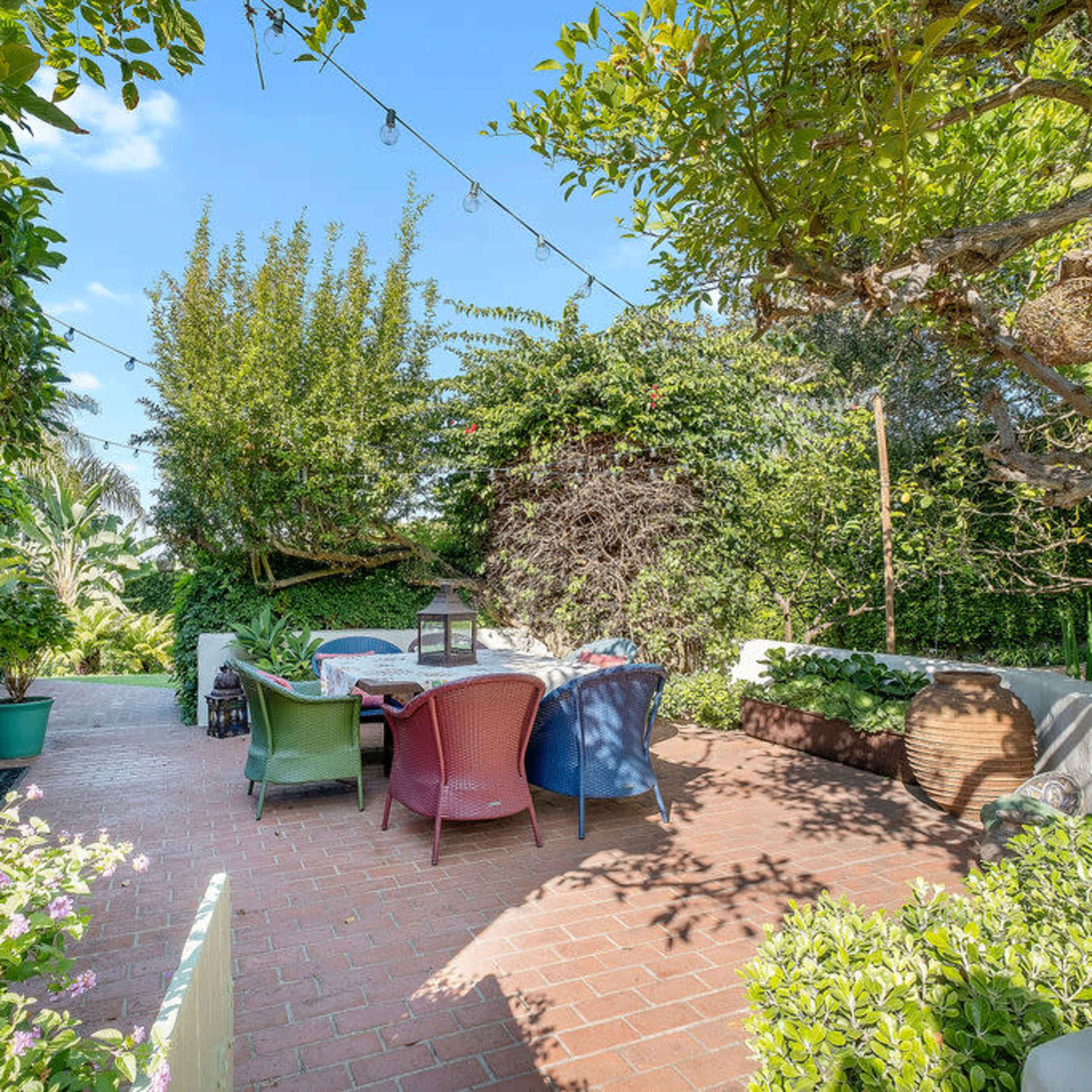 A patio area with colorful chairs and tables surrounded by greenery and flowers.