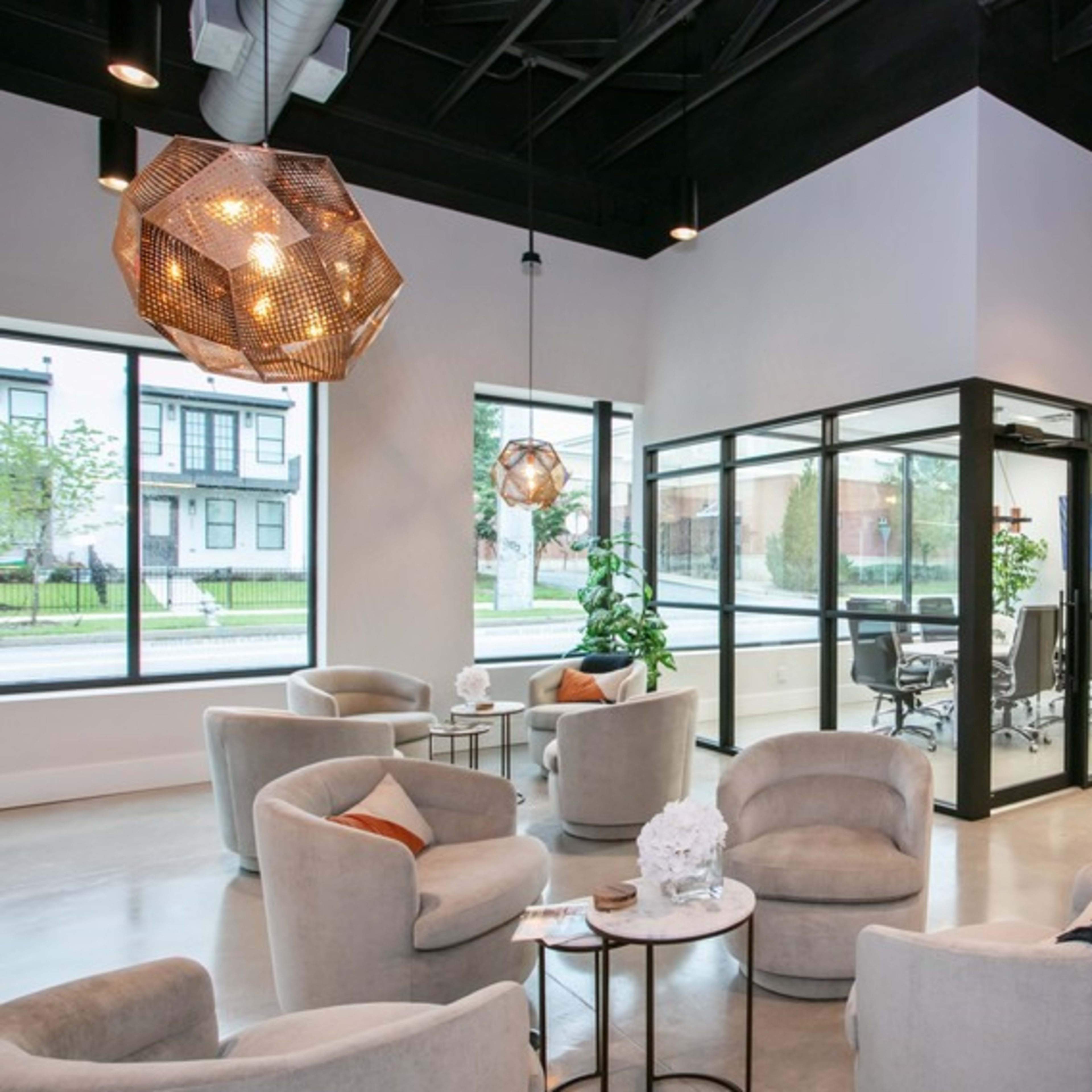A modern office space with a glass-walled conference room, comfortable seating areas, and decorative plants.
