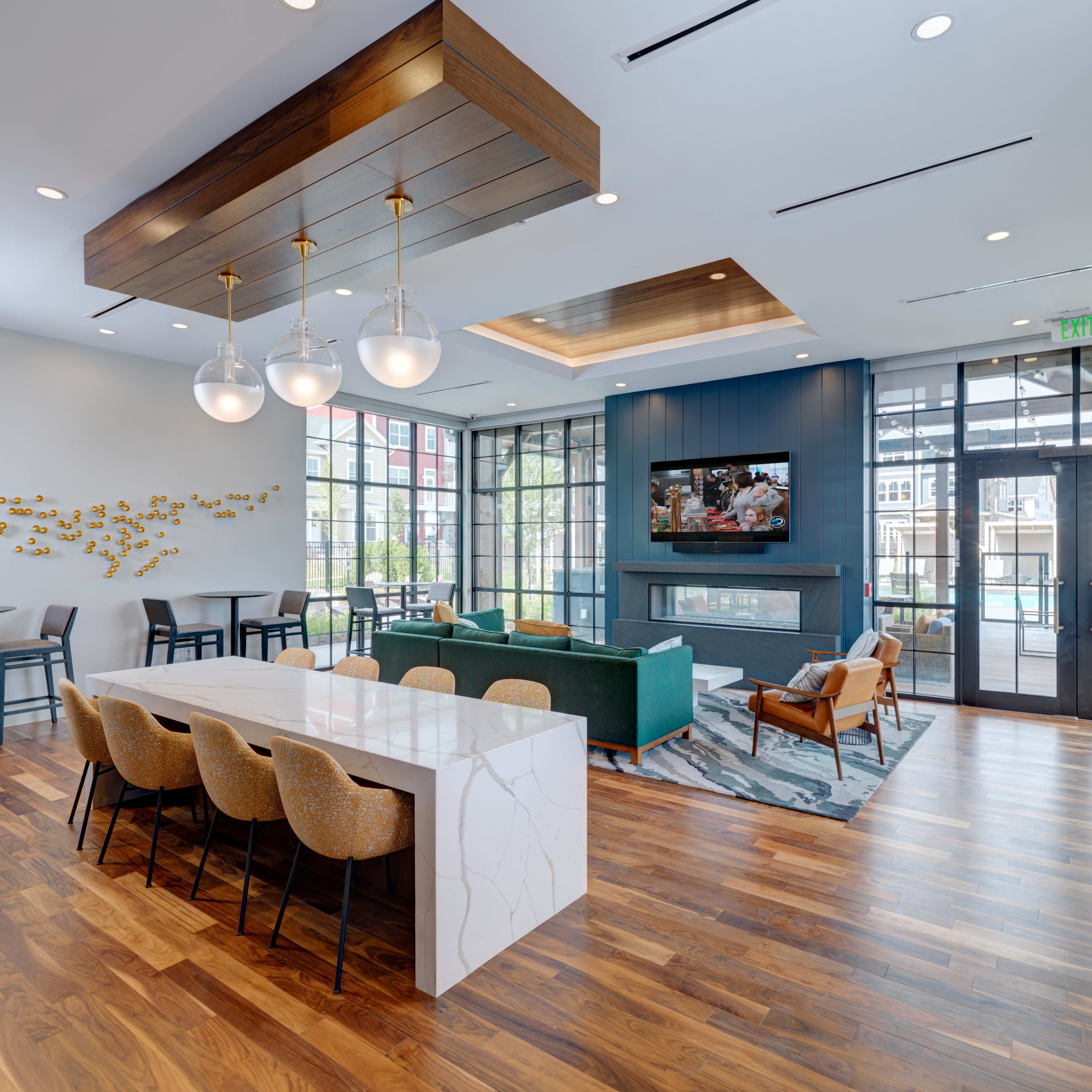 A modern common area with a seating arrangement, a large table, and windows that provide natural light.