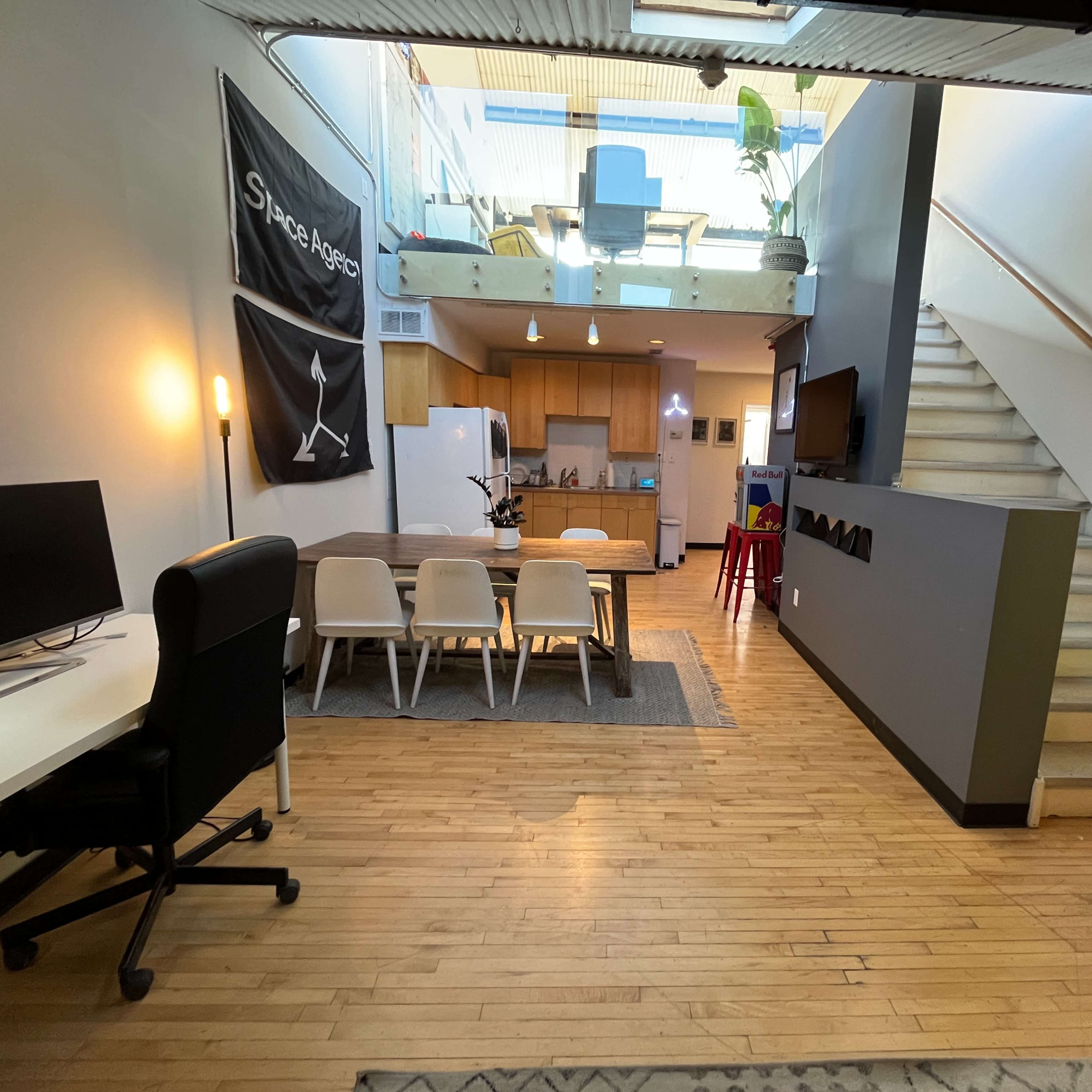 A spacious, modern living area with a dining table, kitchen, and a staircase leading to an upper level.